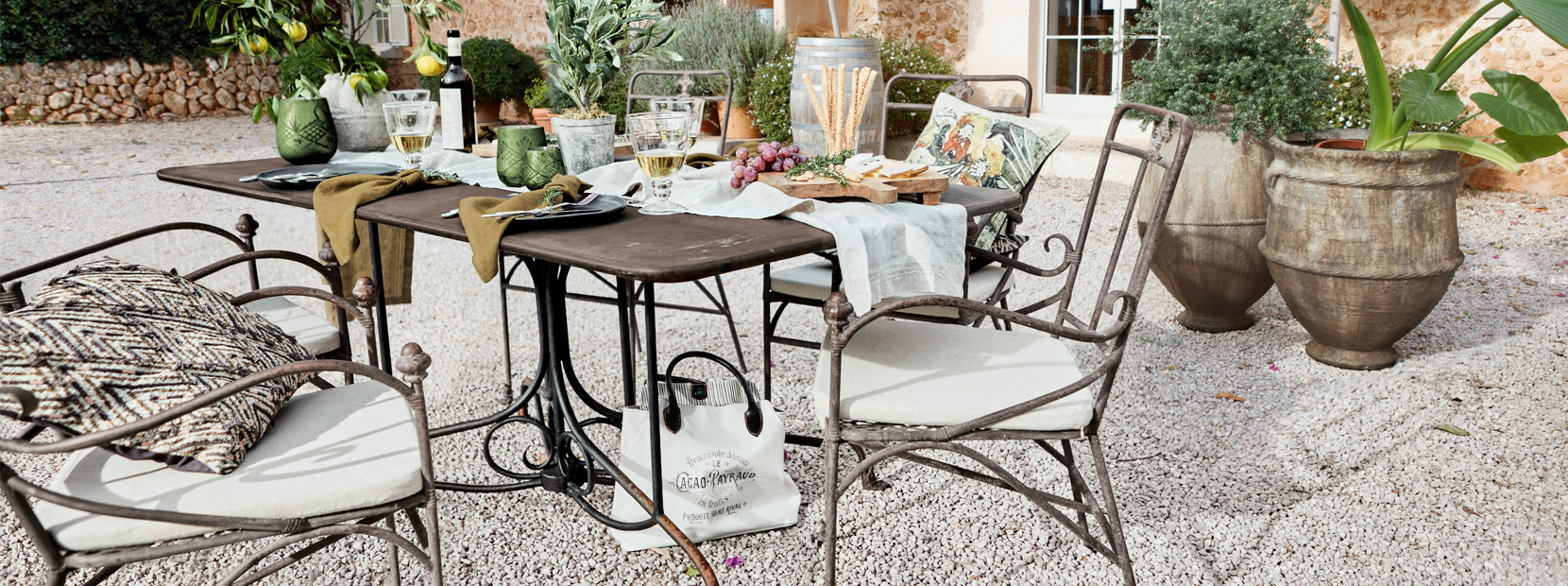 Mesa de jardín con sillas de metal y decoración mediterránea en patio de grava