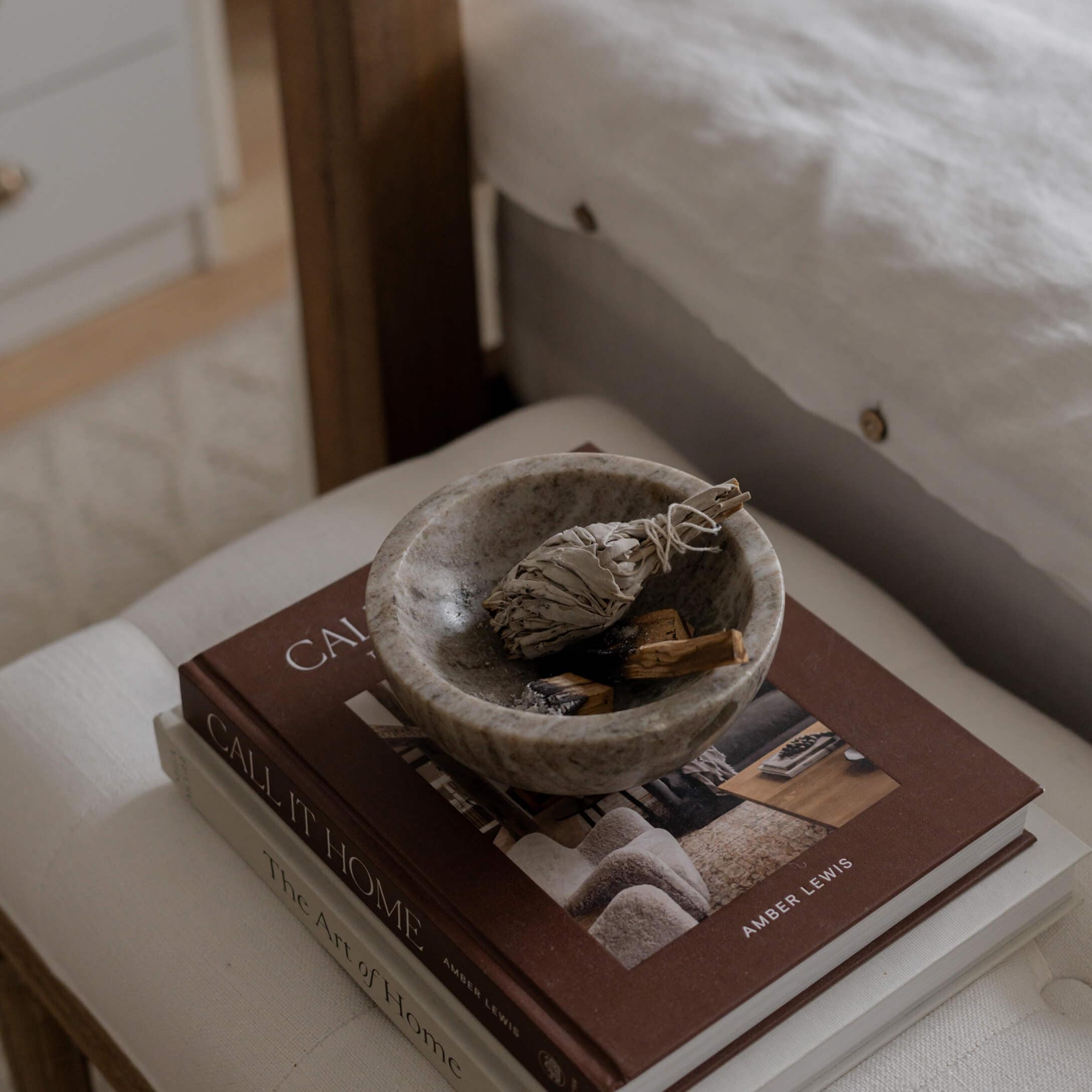Cuenco de piedra gris con hierbas secas sobre libros de decoración del hogar