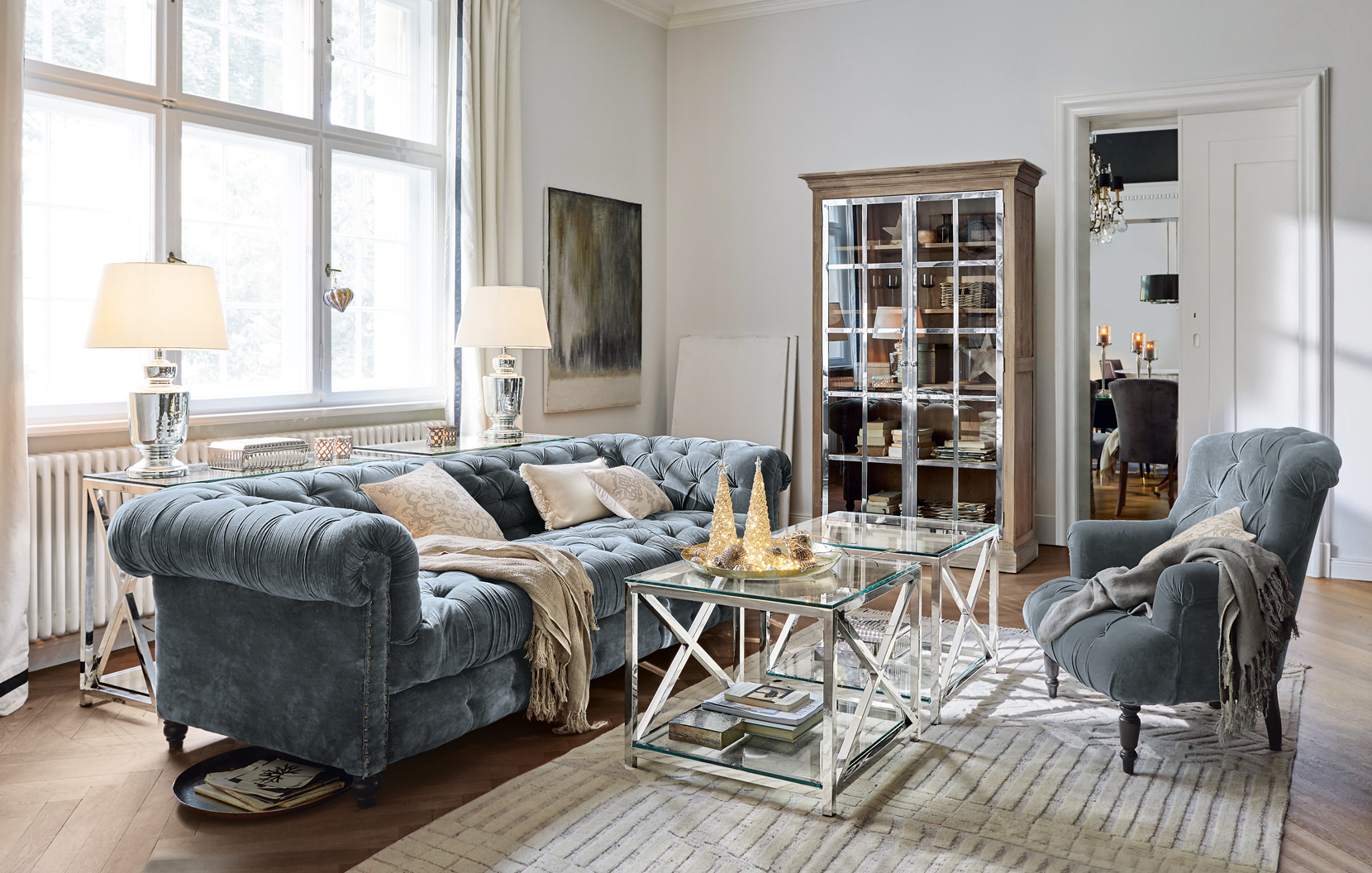Salón elegante con sofá de terciopelo azul y mesas de centro de cristal en estilo clásico