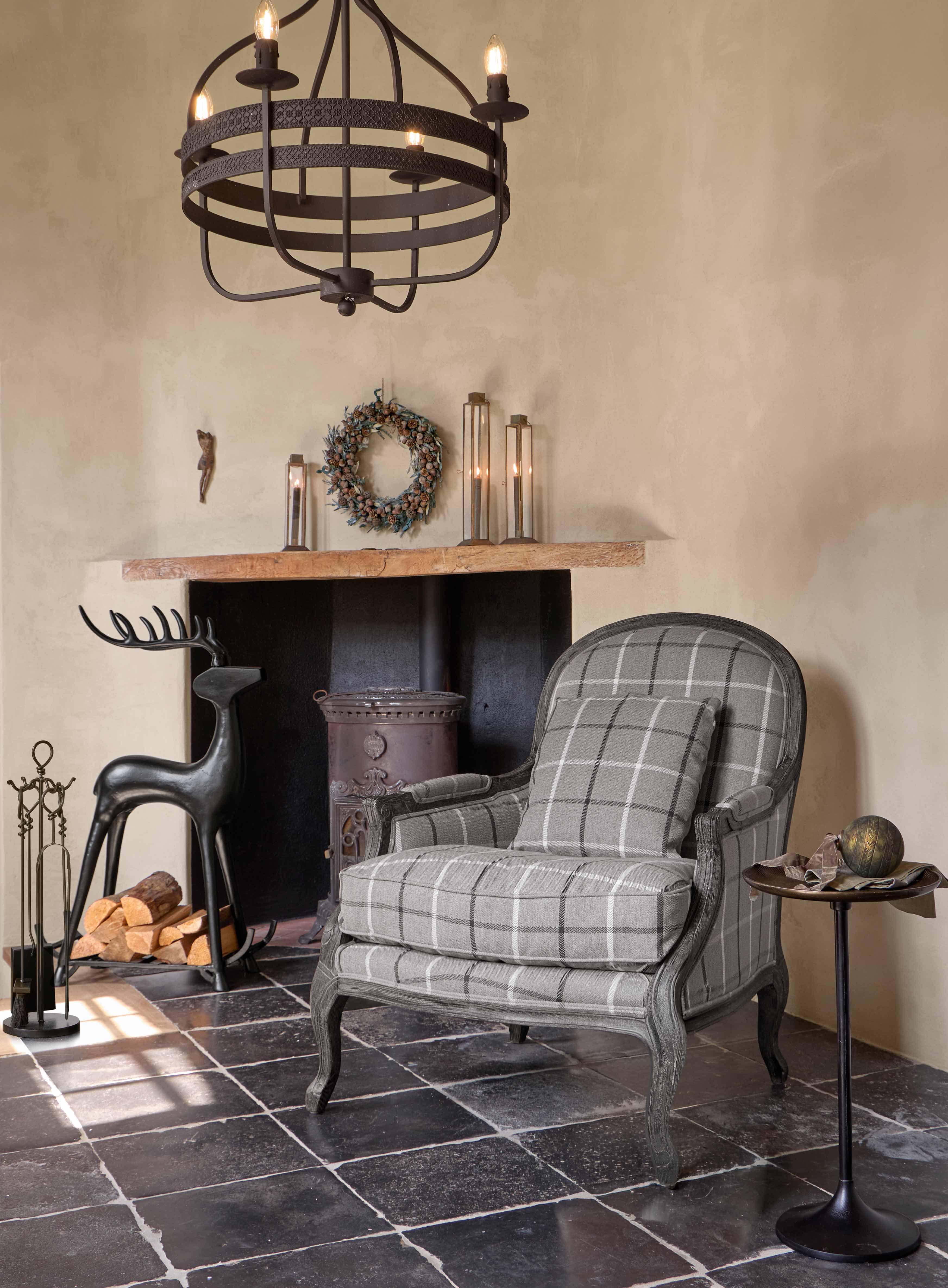 Sillón gris a cuadros con estructura de madera en estilo clásico en salón acogedor con chimenea