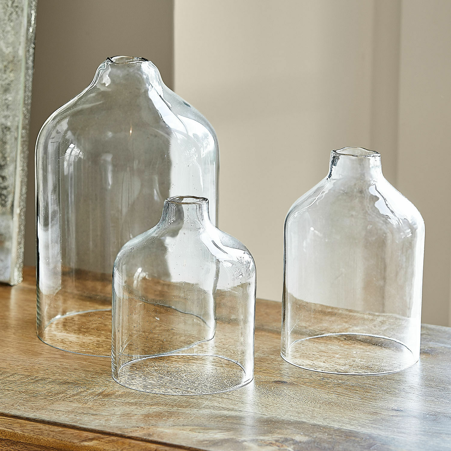 Set de 3 portavelas Xalvent Conjunto de tres jarrones de vidrio transparente de diferentes tamaños sobre mesa de madera