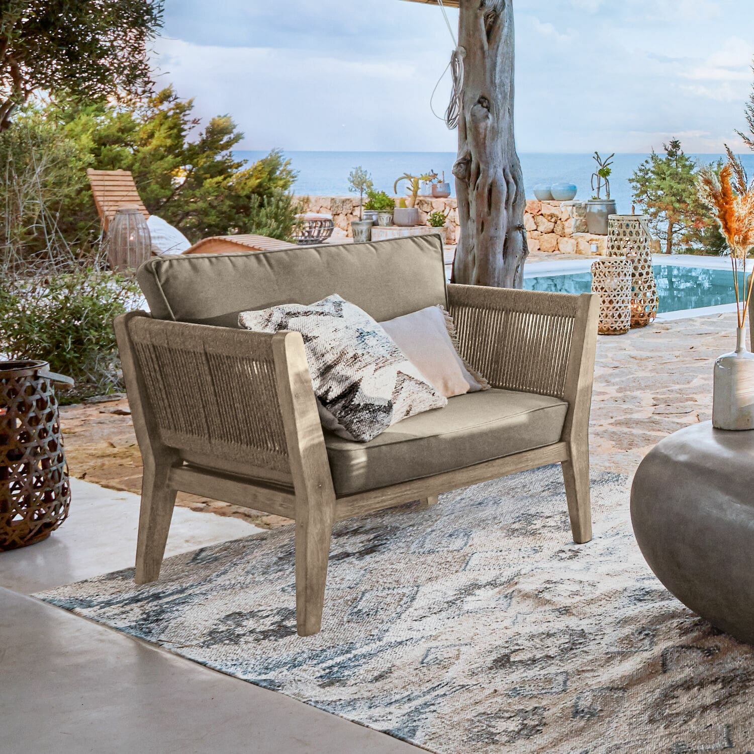 Sillón FSC® 100% Biarritz Sofá de exterior de madera y tela beige en terraza con vista al mar