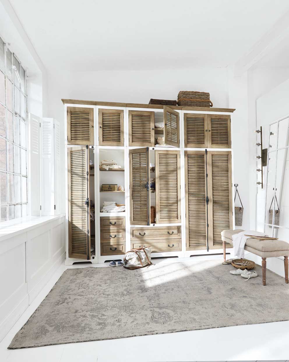 Gran armario de madera con marco blanco y puertas de persiana en habitación luminosa y natural