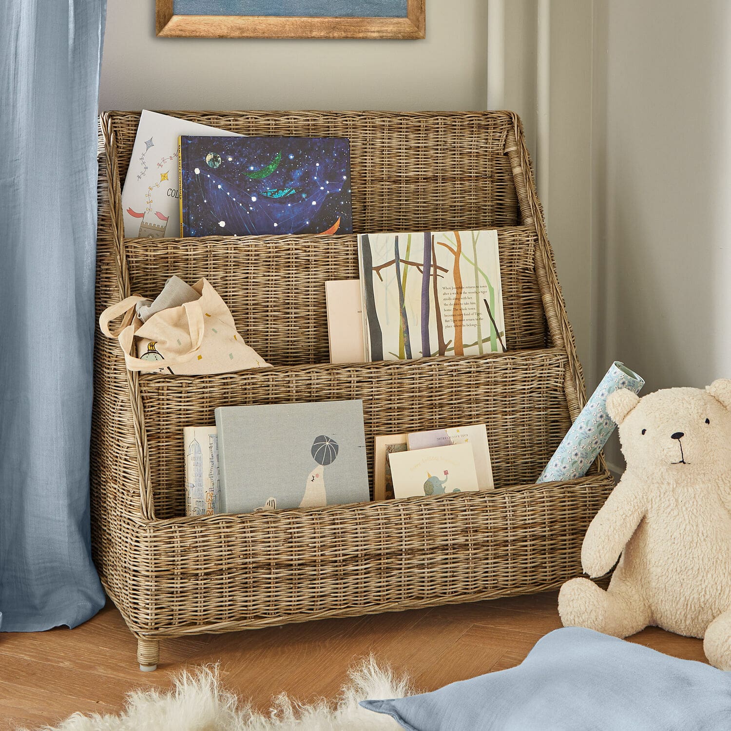 Estante Trésolia Estantería de ratán natural de tres niveles con libros y oso de peluche en habitación infantil