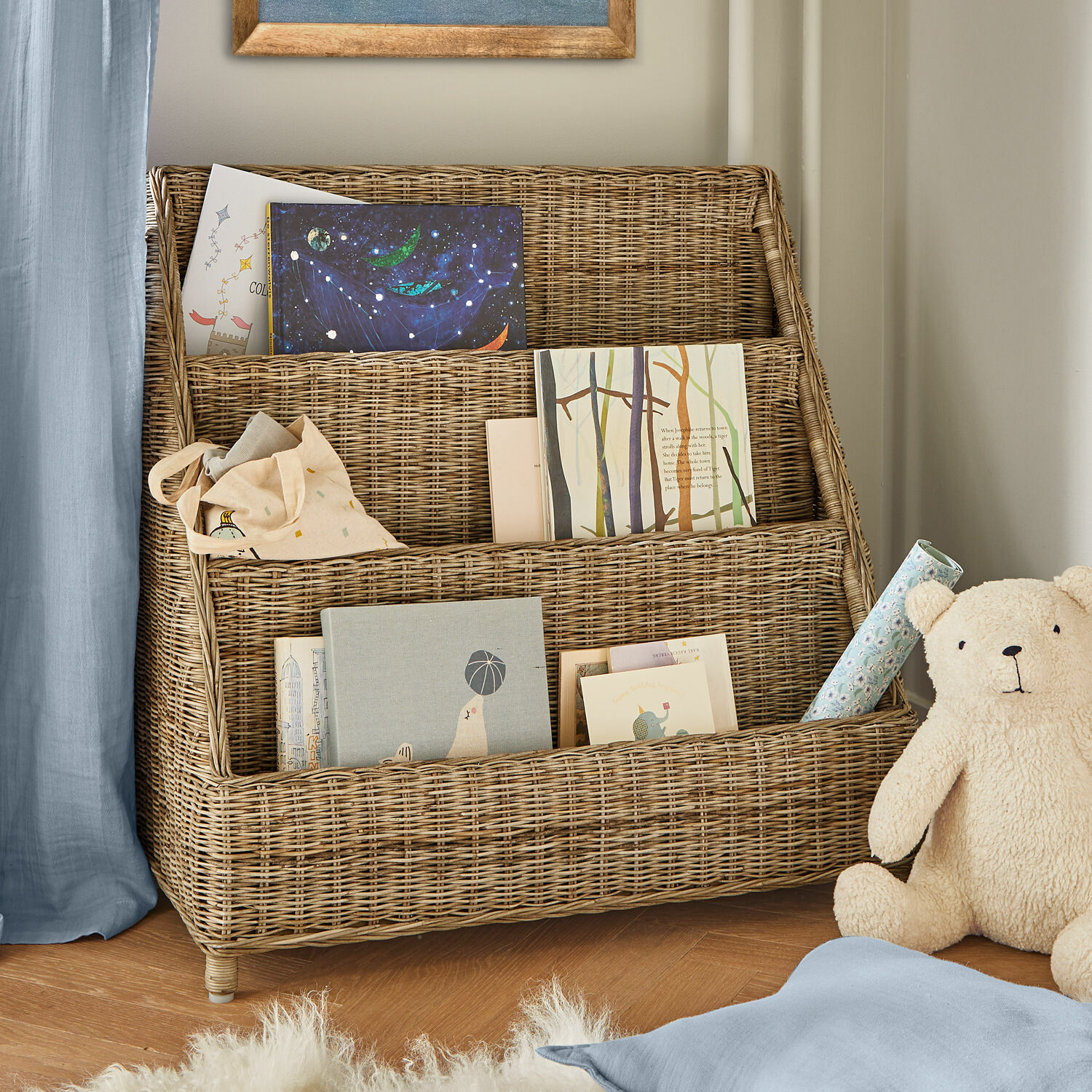 Estante Trésolia Estantería de ratán natural de tres niveles con libros y oso de peluche en habitación infantil