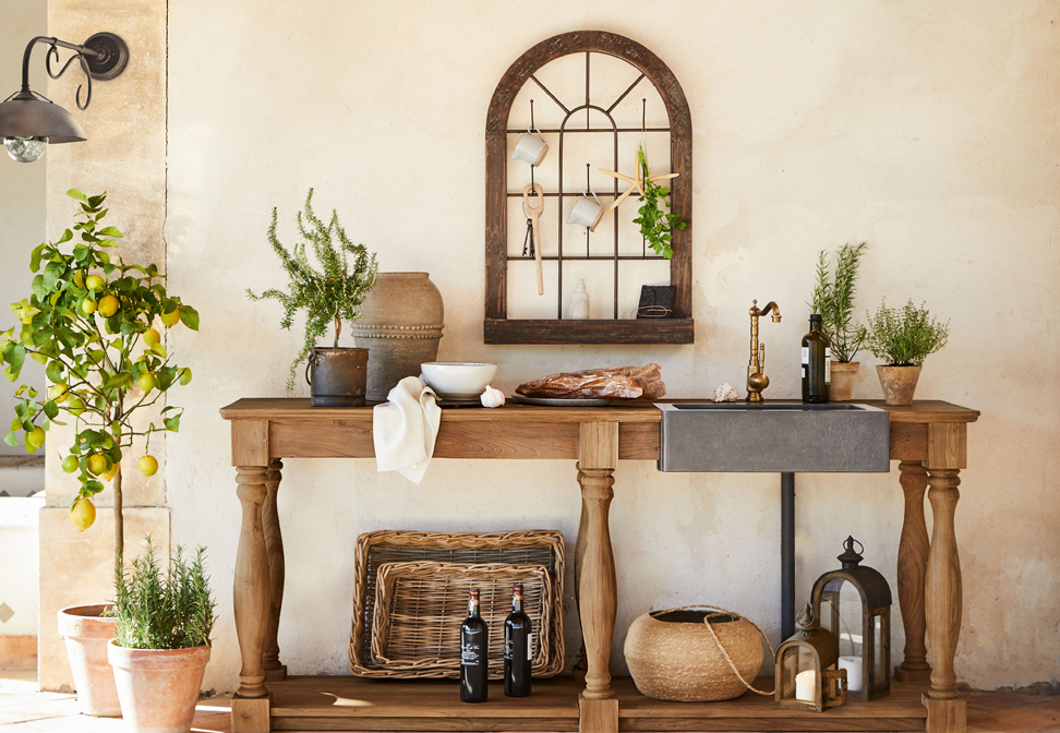 Mesa de madera con fregadero de hormigón y grifo de cobre estilo mediterráneo con plantas y decoraciones