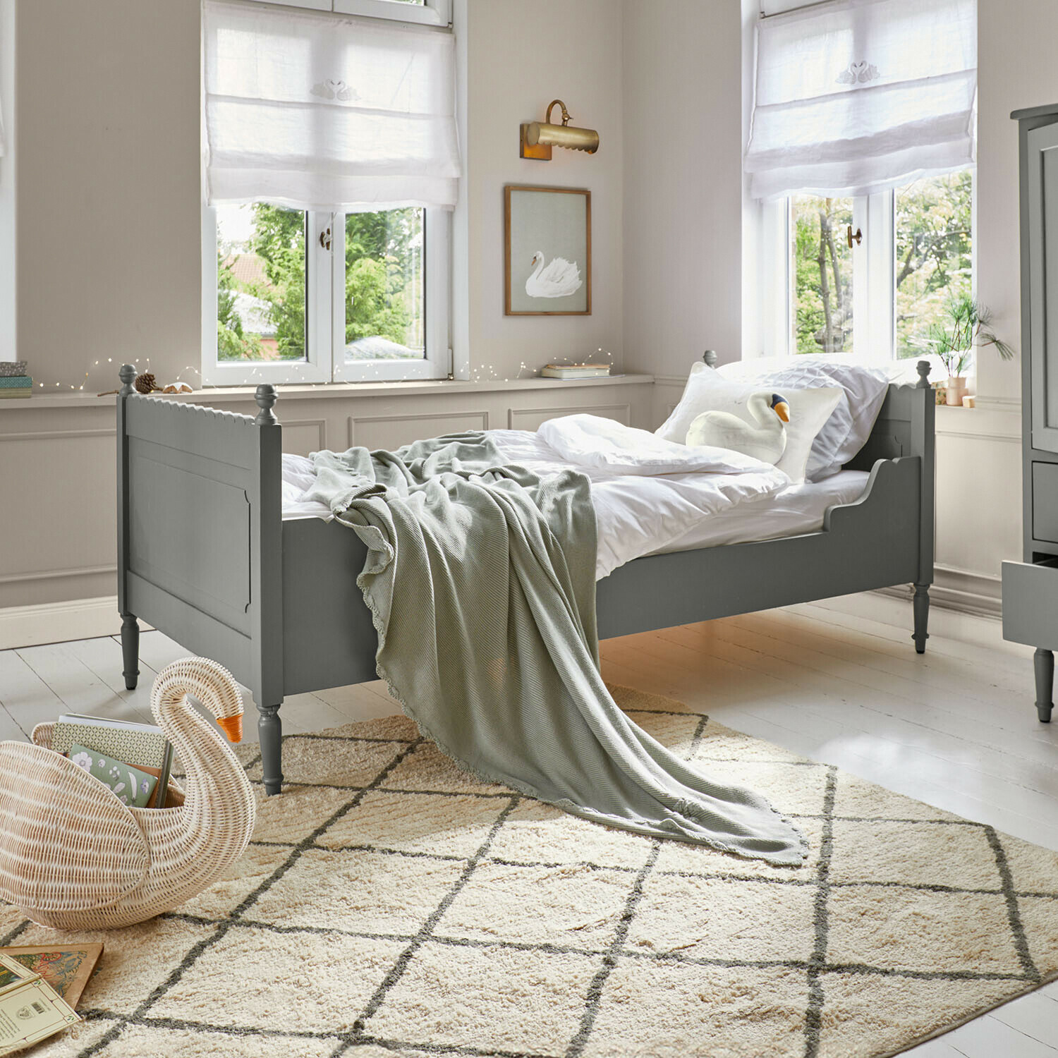 Cama individual Kystlund Cama de madera verde con ropa de cama blanca y manta gris en habitación luminosa con alfombra
