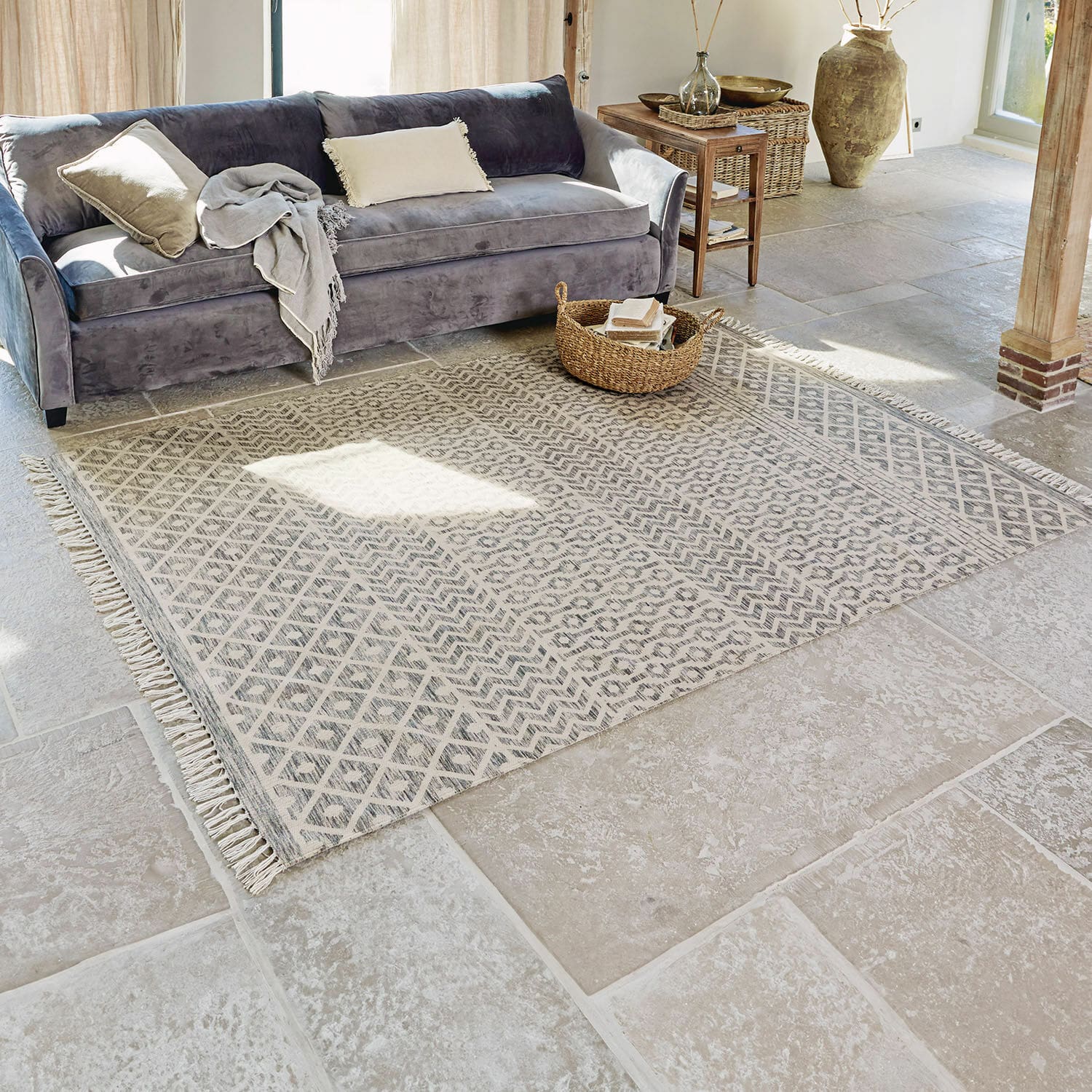 Alfombra para interior y exterior Champigny Alfombra beige con patrón geométrico y flecos sobre suelo de piedra en sala luminosa