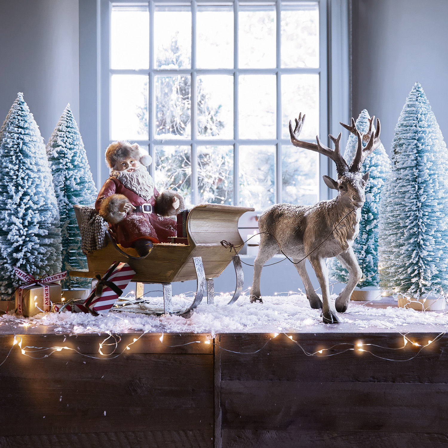 Trineo de Navidad Palaima Figura de Papá Noel con abrigo rojo en trineo de madera con reno y árboles nevados decorativos