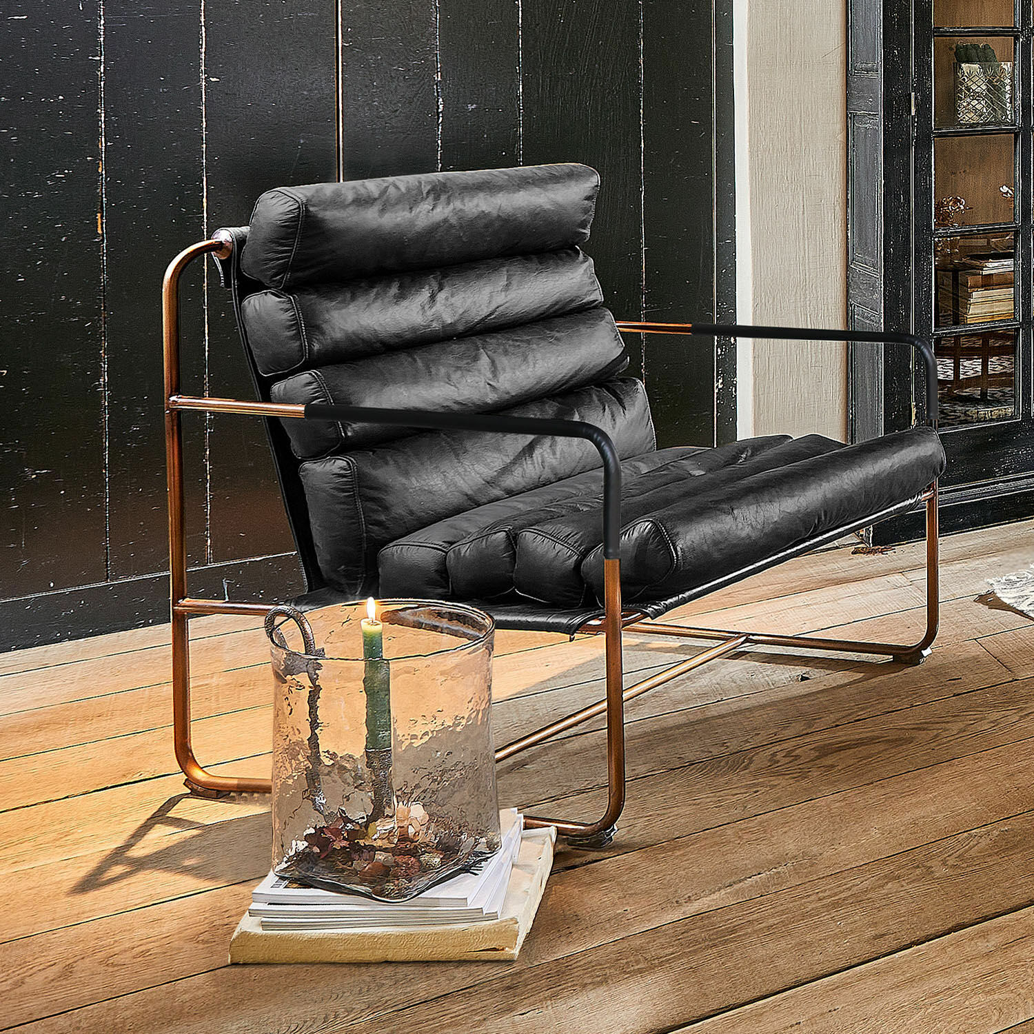 Sillón Jelvano Sillón de cuero negro con estructura de cobre sobre suelo de madera en interior moderno