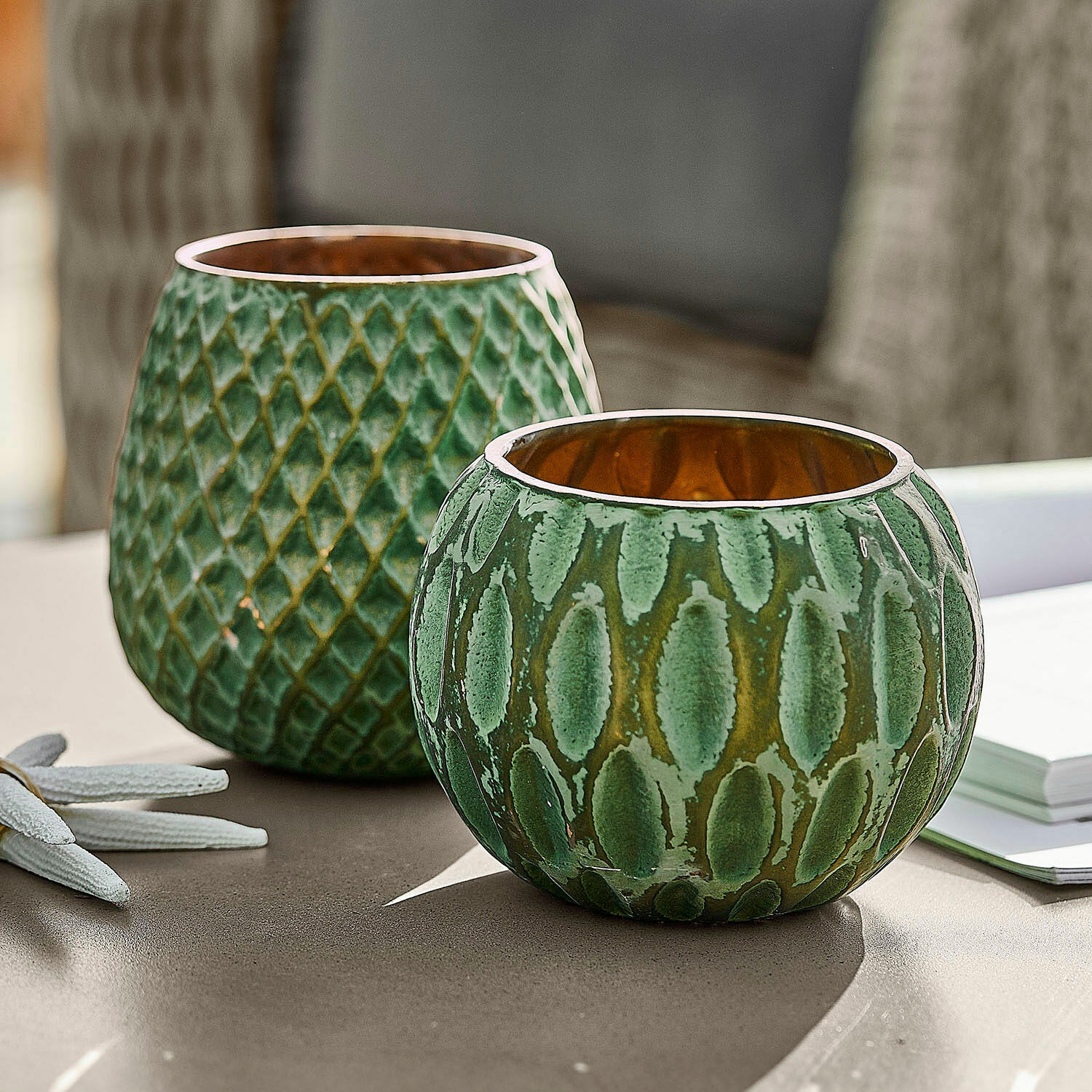Set de 2 portavelas Xerice Conjunto de dos portavelas de cerámica verde con textura y interior dorado sobre mesa