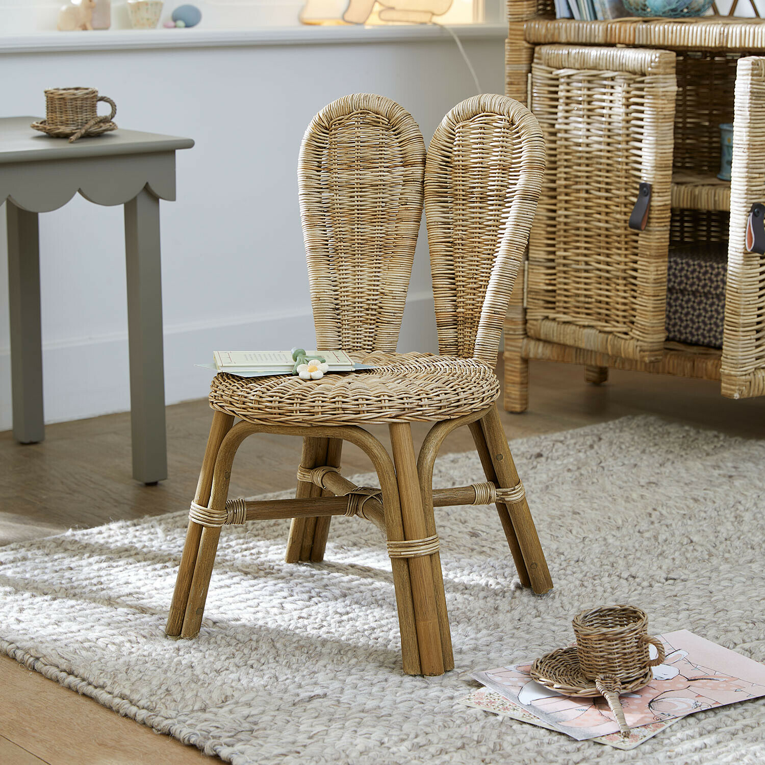 Silla infantil Papillonette Silla infantil de ratán natural sobre alfombra clara en habitación infantil
