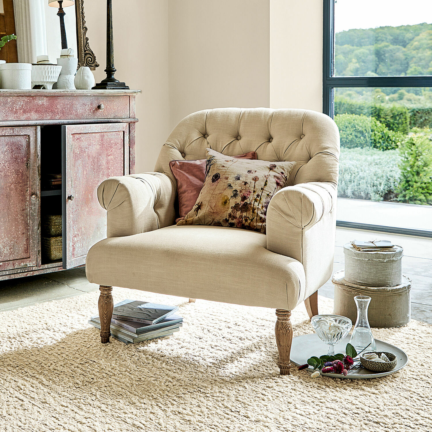 Sillón Shambrook Sillón tapizado beige con patas de madera y cojines decorativos en sala luminosa