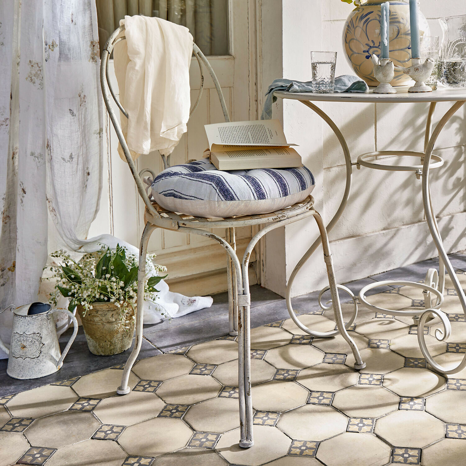 Silla Aube Silla metálica vintage con cojín a rayas azul y blanco y tela blanca sobre el respaldo en habitación luminosa
