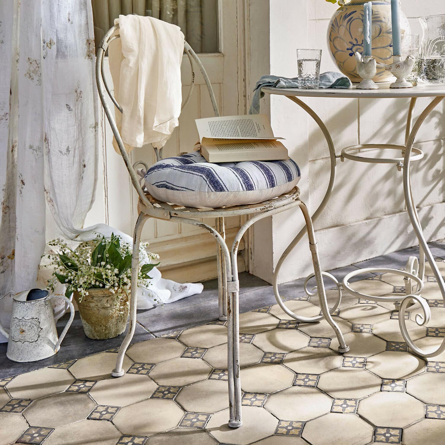 Silla Aube Silla metálica vintage con cojín a rayas azul y blanco y tela blanca sobre el respaldo en habitación luminosa
