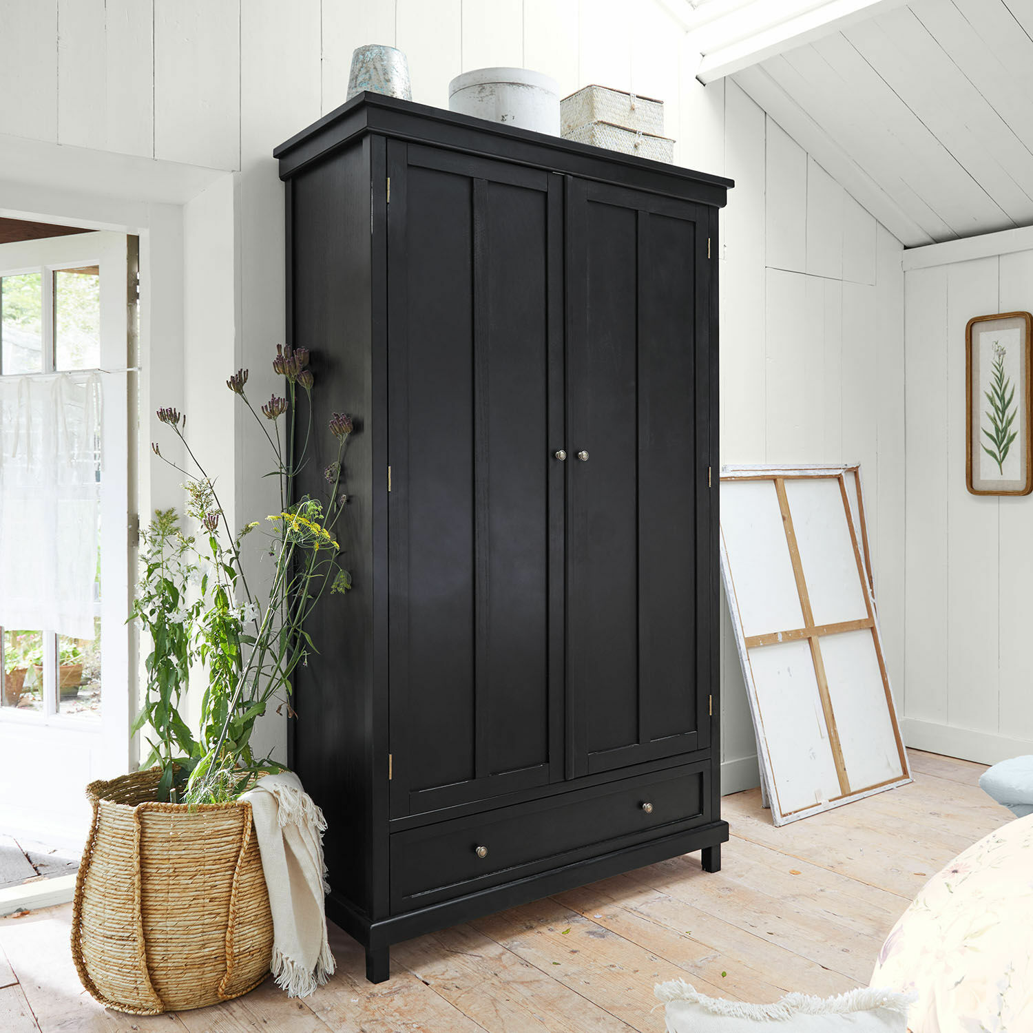 Armario Sirevol Armario negro de madera con dos puertas y cajón en habitación luminosa y acogedora