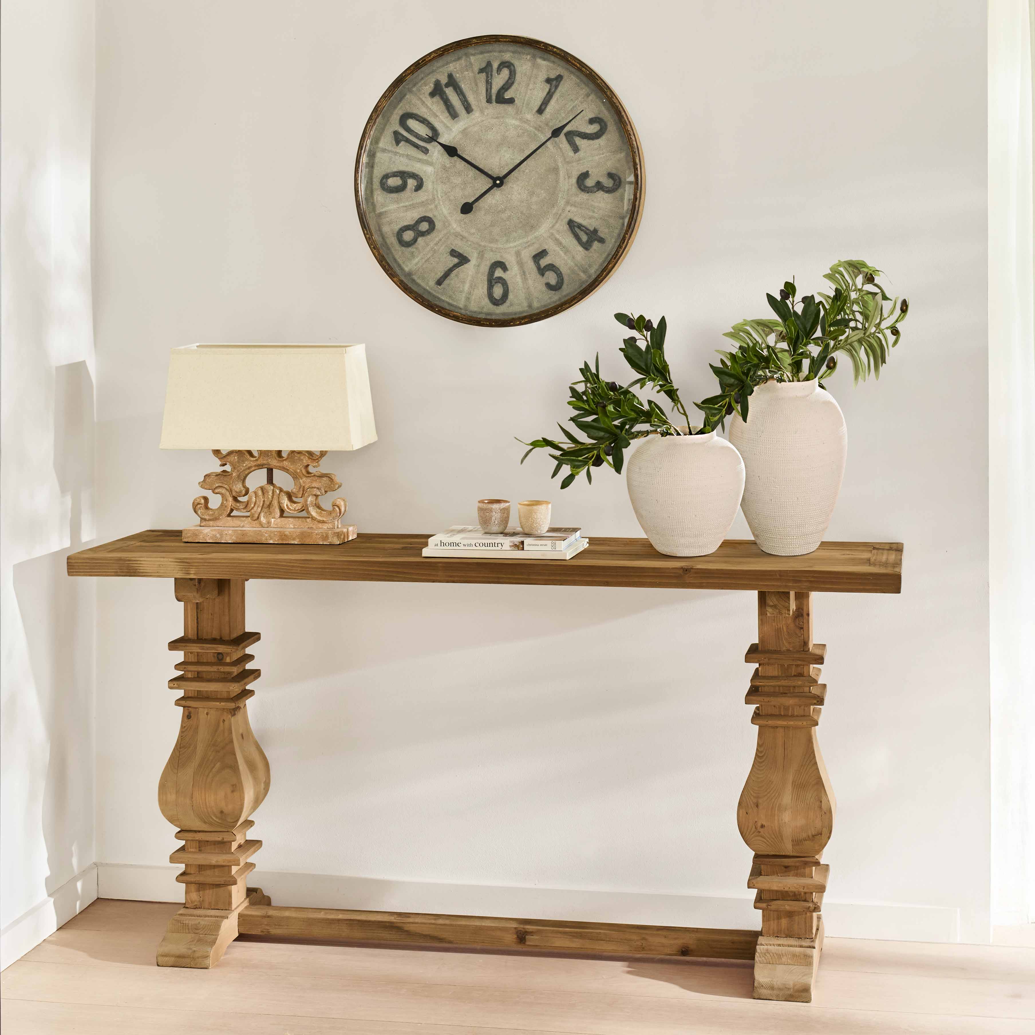 Consola de madera maciza con patas decorativas, jarrones blancos de cerámica y lámpara sobre fondo claro