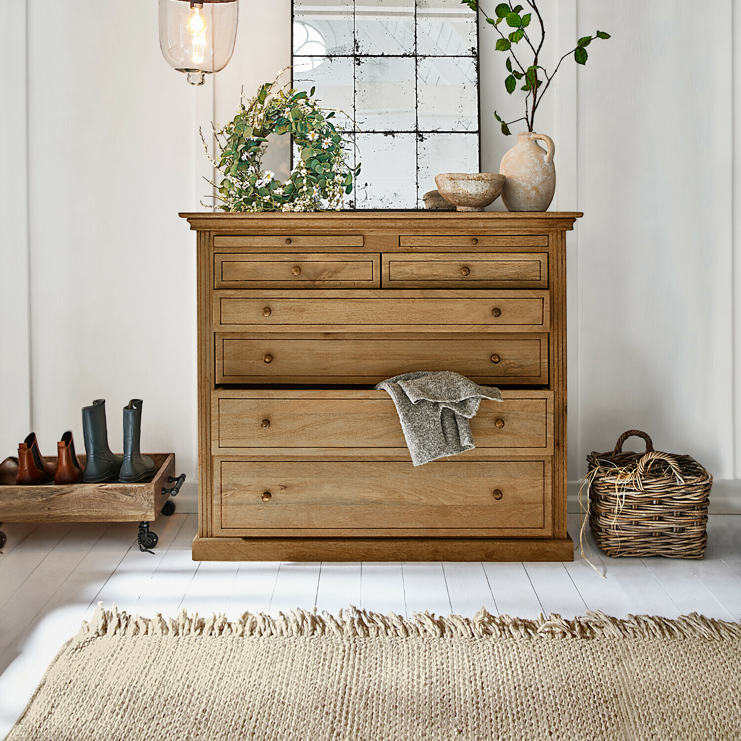 Cómoda Espoirin Cómoda de madera natural con varios cajones, decoraciones y alfombra clara en interior luminoso