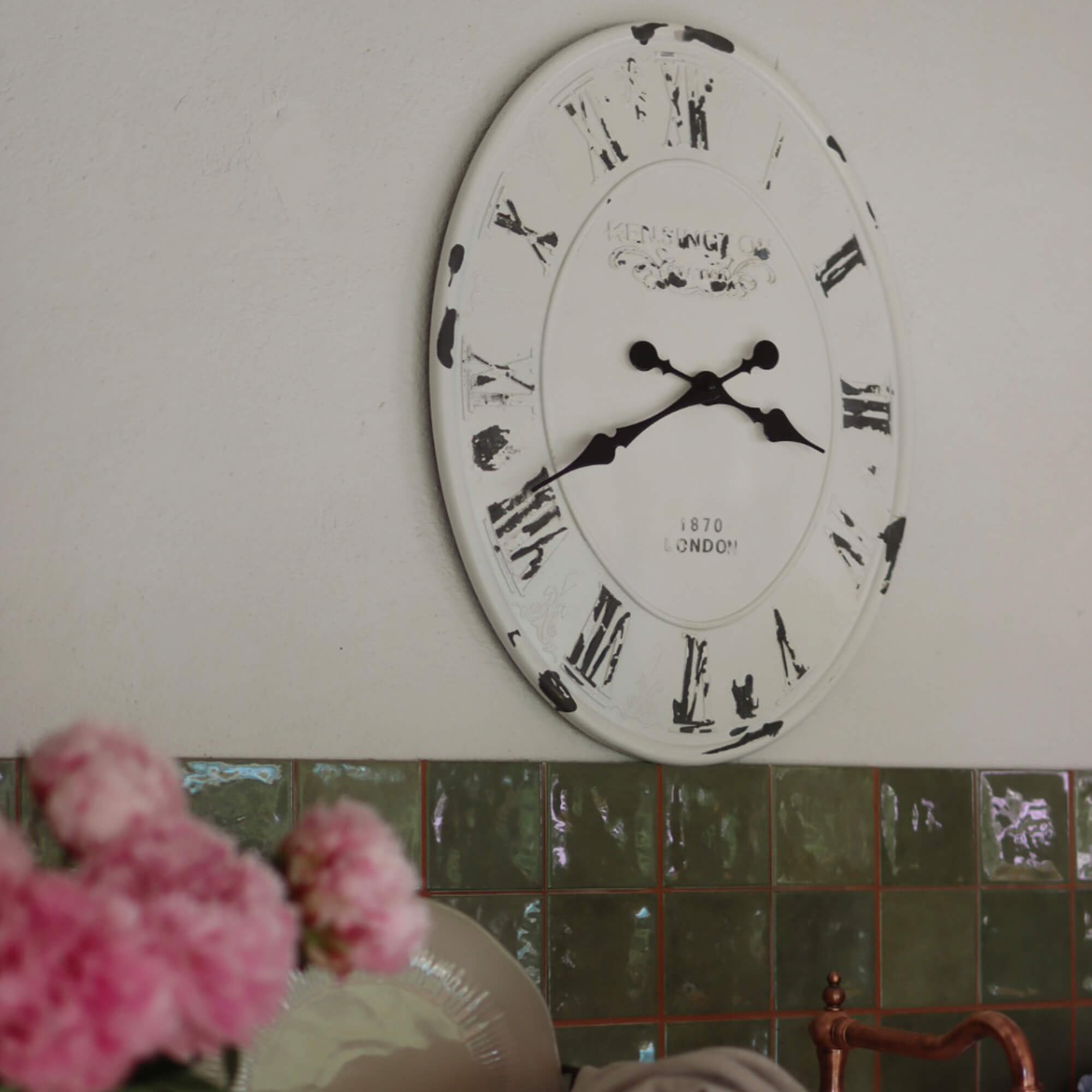 Reloj de pared metálico blanco con números romanos negros y acabado envejecido para decoración interior