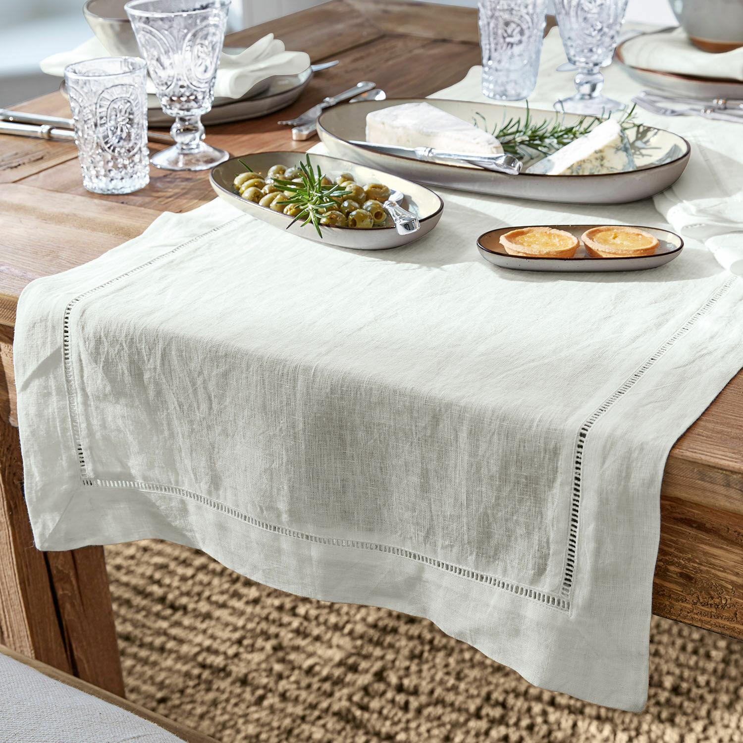 Camino de mesa Covent Garden Camino de mesa de lino blanco sobre mesa de madera con platos y aperitivos, decoración elegante