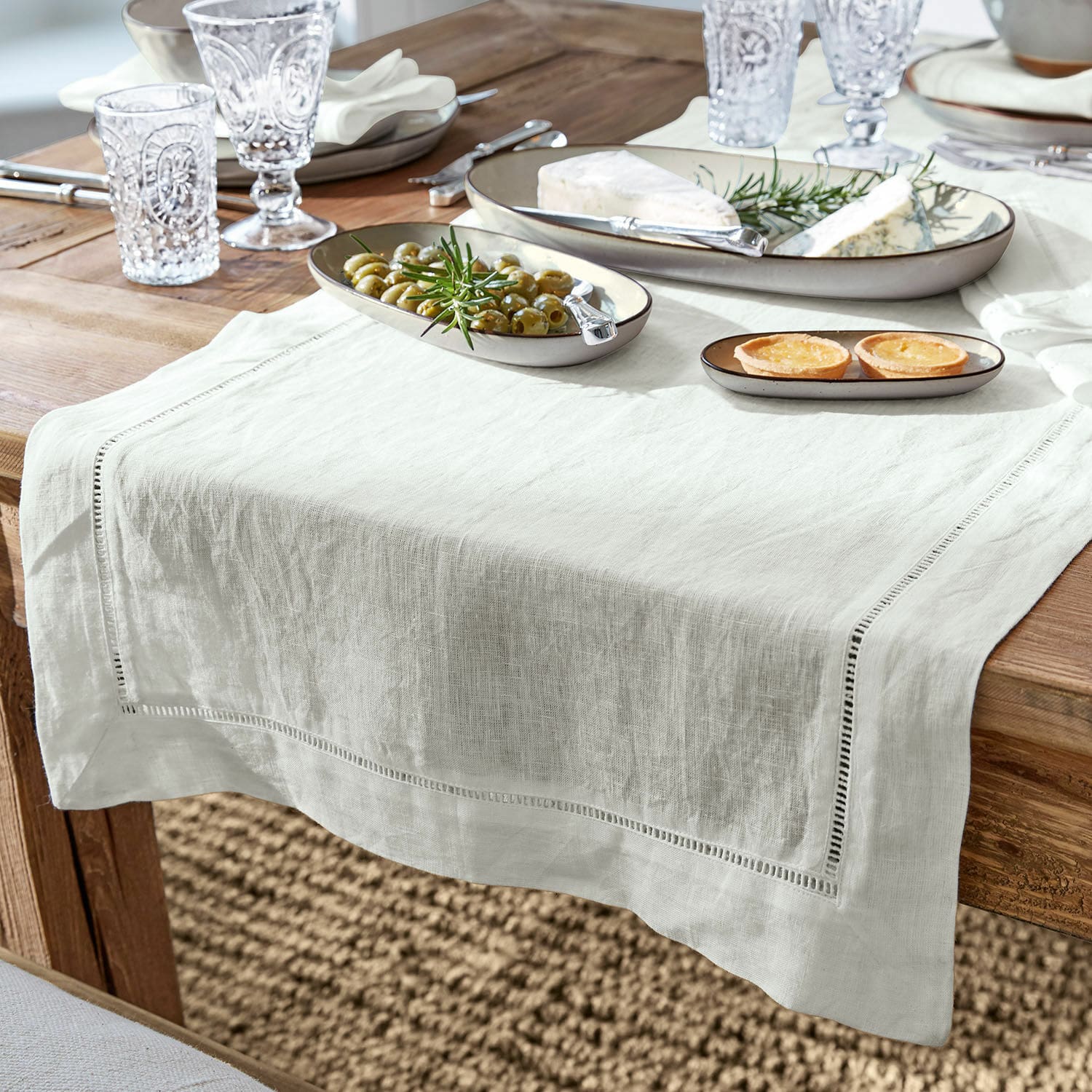 Camino de mesa Covent Garden Camino de mesa de lino blanco sobre mesa de madera con platos y aperitivos, decoración elegante