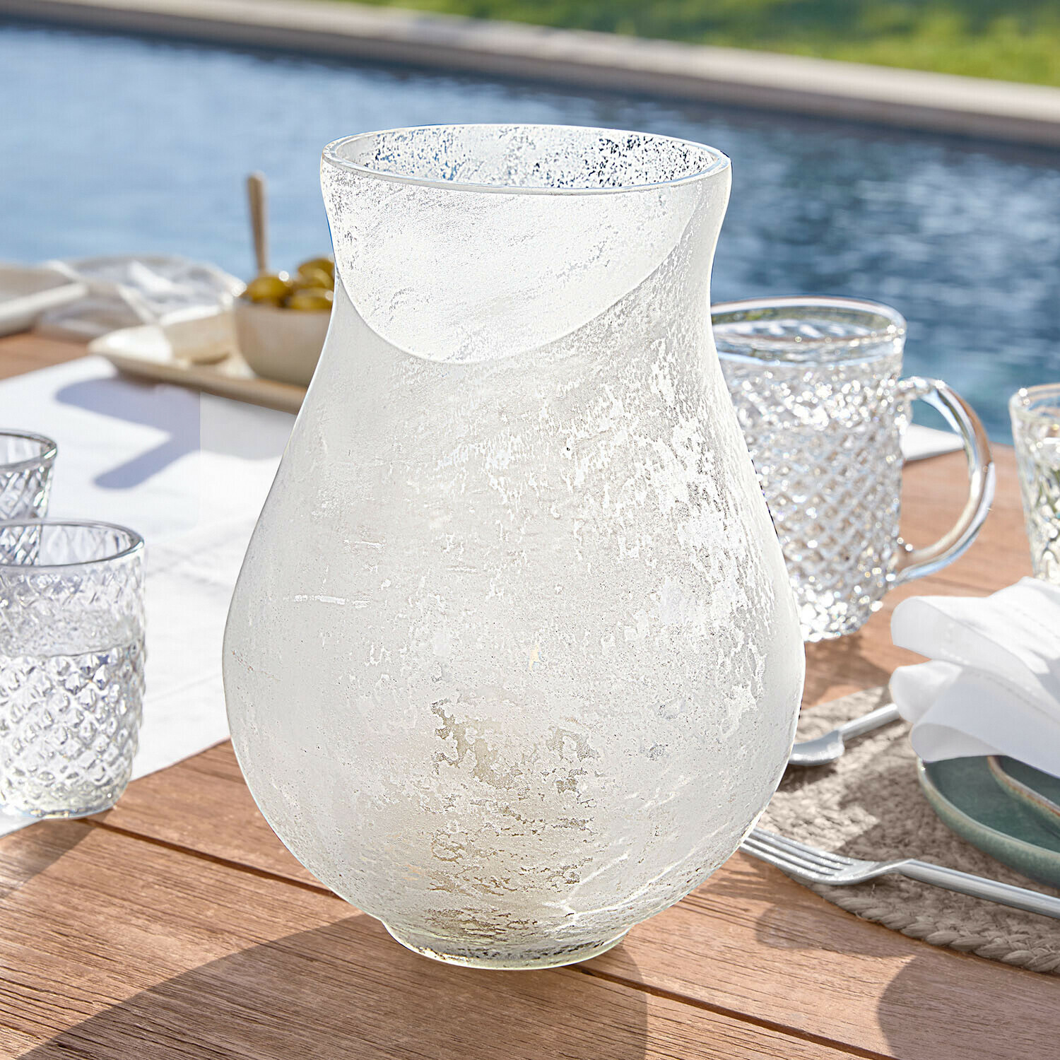 Portavelas Nareli Jarra transparente de vidrio esmerilado sobre mesa de madera junto a la piscina, vaso para bebidas