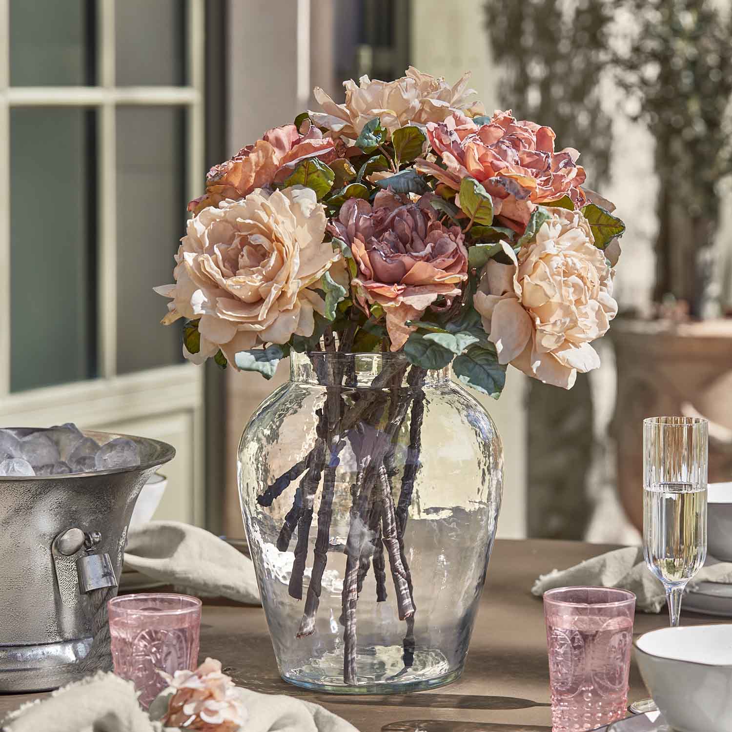 Ramo de rosas en jarrón de cristal sobre mesa, decoración floral en tonos pastel