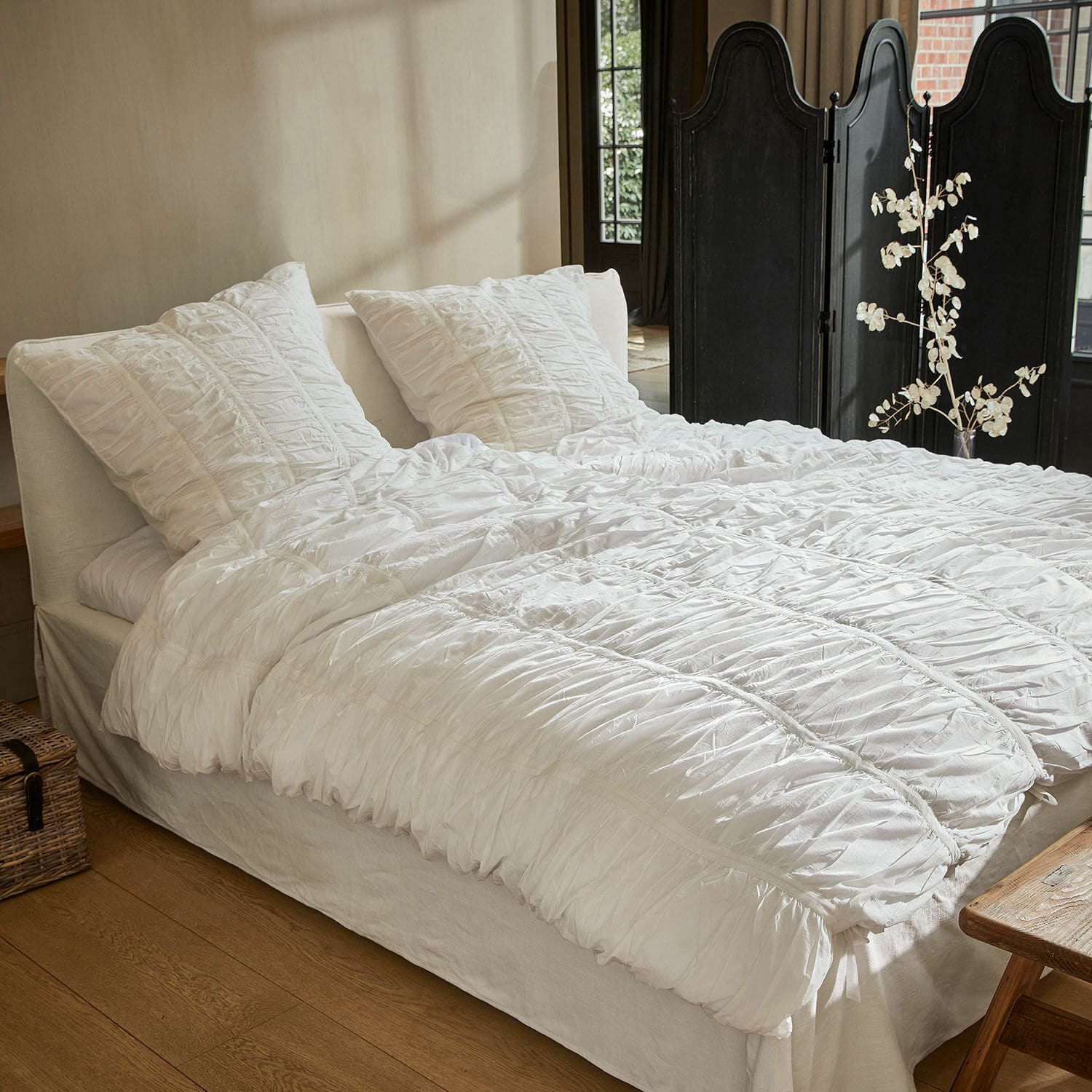 Ropa de cama Magdelen Ropa de cama blanca de algodón con fruncidos sobre cama en dormitorio acogedor
