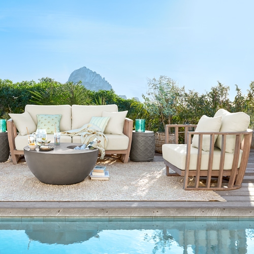 Conjunto de muebles de jardín con cojines beige y estructura de madera junto a la piscina en la terraza