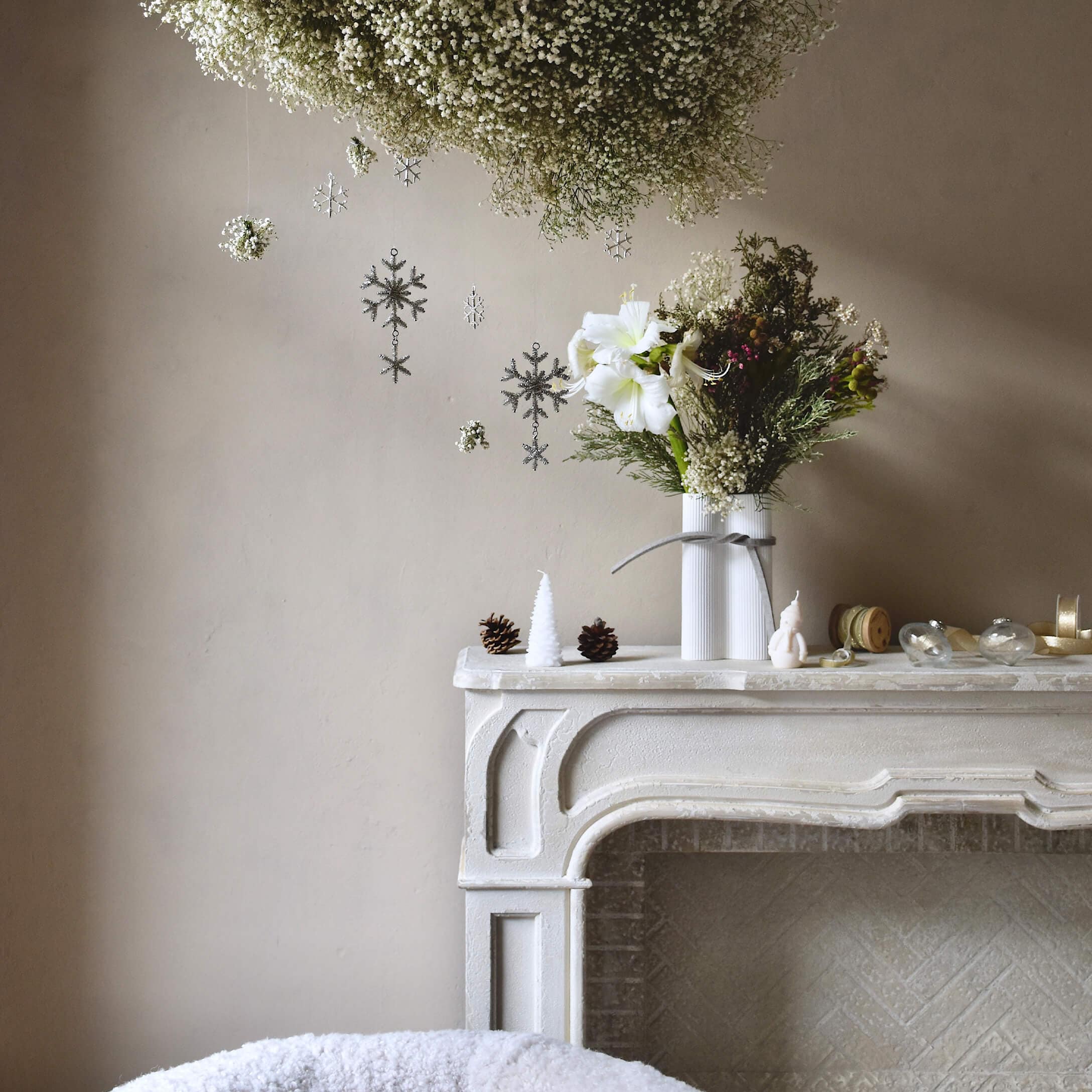 Chimenea blanca decorativa con jarrón y flores, decoraciones navideñas con piñas y velas