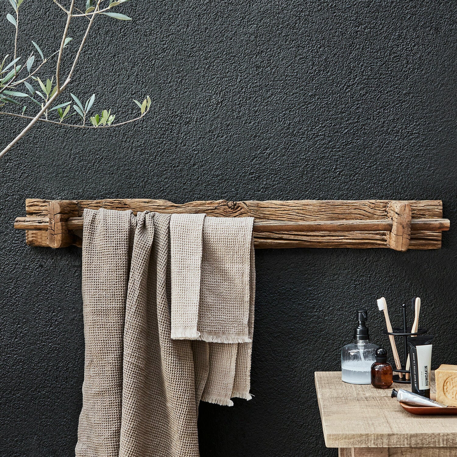 Toallero Einid Toallero rústico de madera natural en pared negra con toallas y accesorios de baño