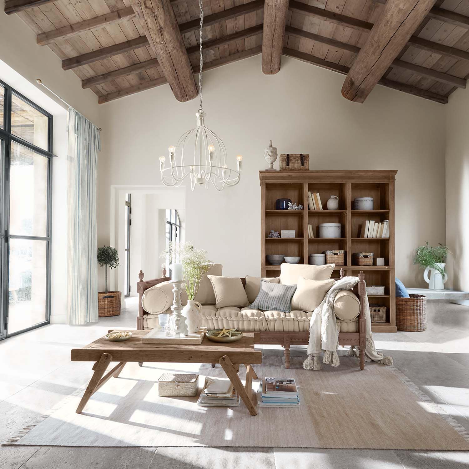 Sala acogedora con mesa de madera y sofá beige bajo techo de madera con vigas expuestas