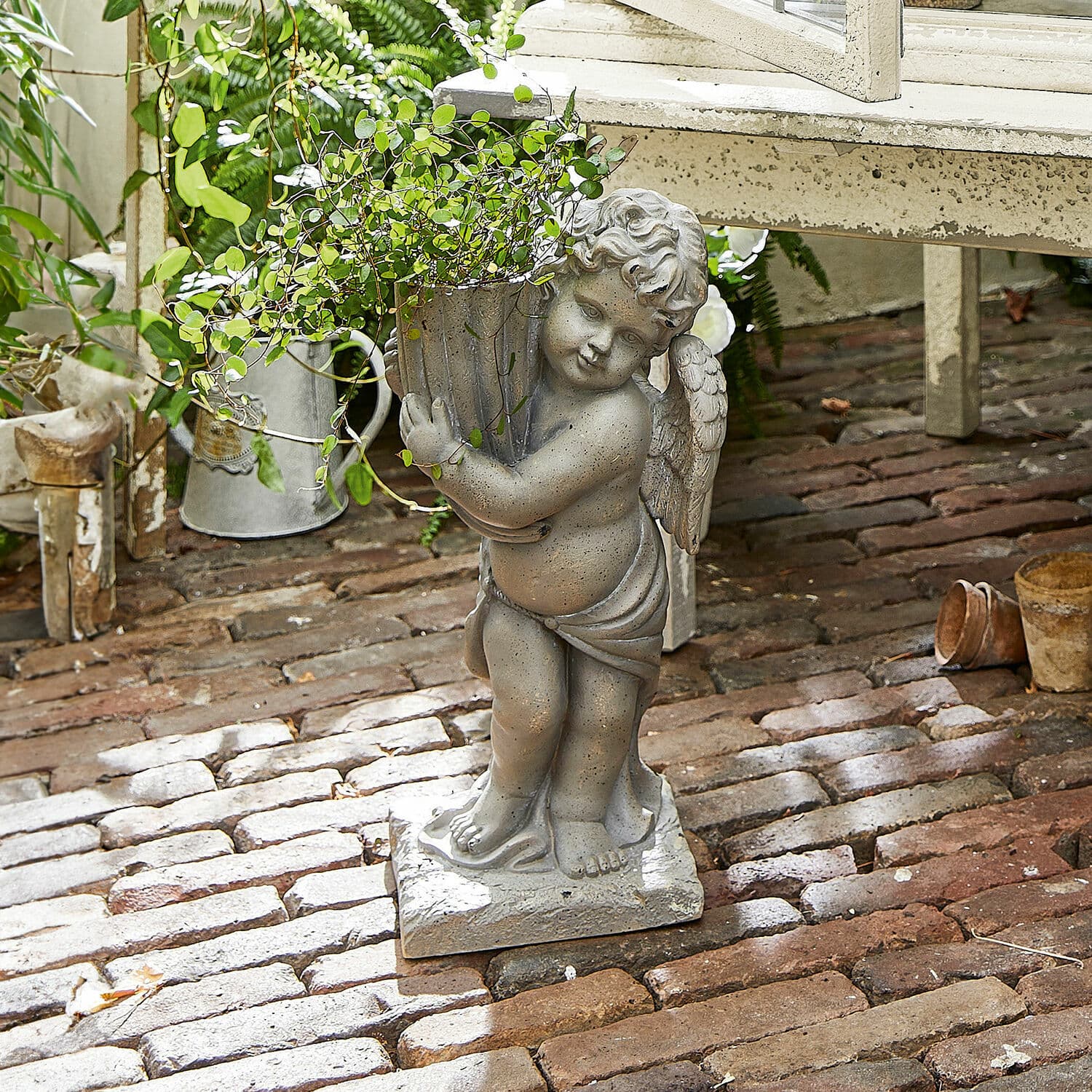 Jardinera Pirie Figura de ángel de piedra gris con maceta y planta verde sobre suelo de ladrillo