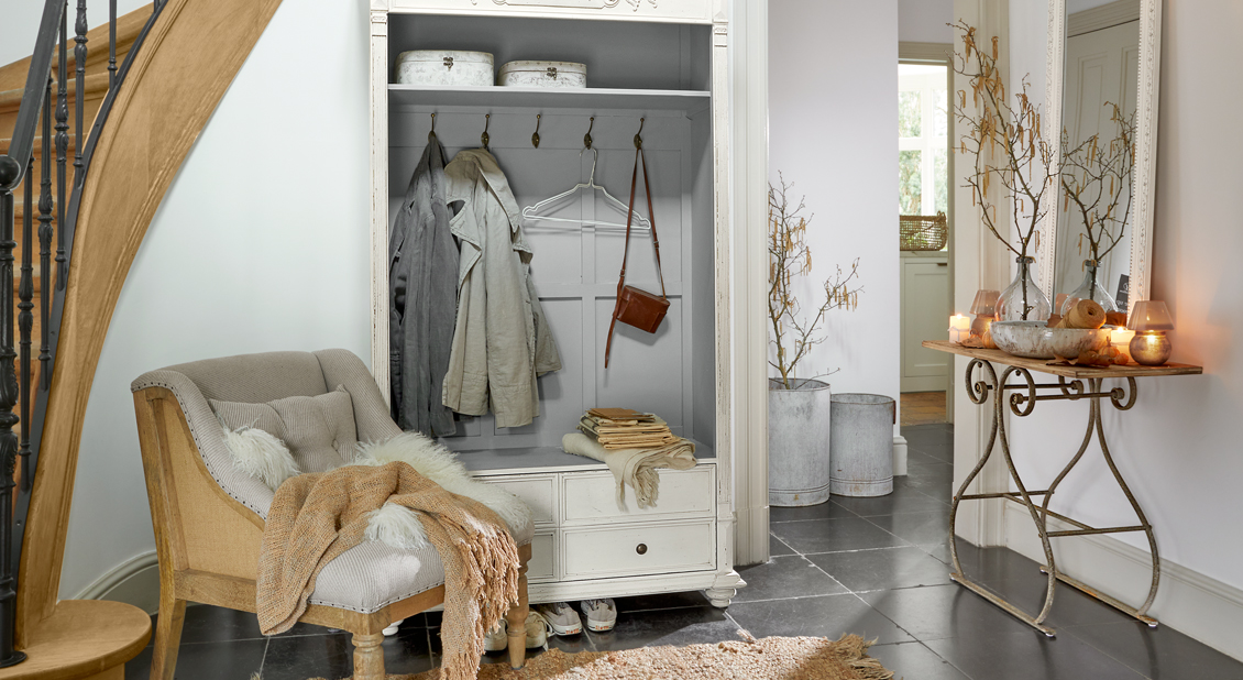 Entrada acogedora con armario blanco de madera y sillón beige vintage sobre suelo oscuro
