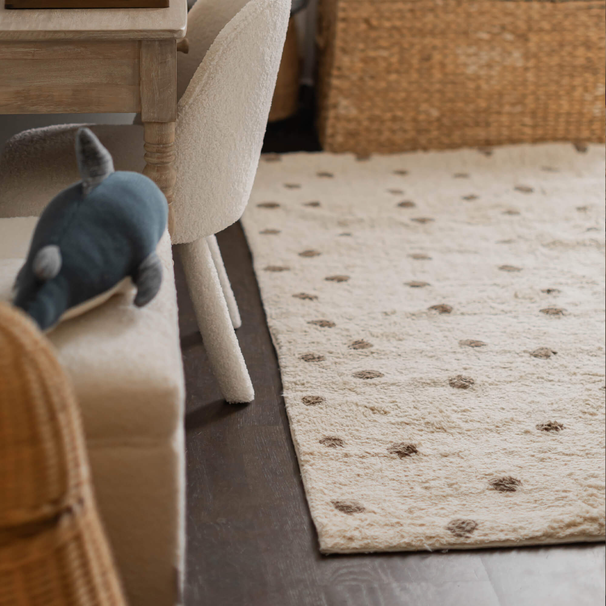 Alfombra beige de material suave con puntos marrones sobre suelo oscuro en sala de estar
