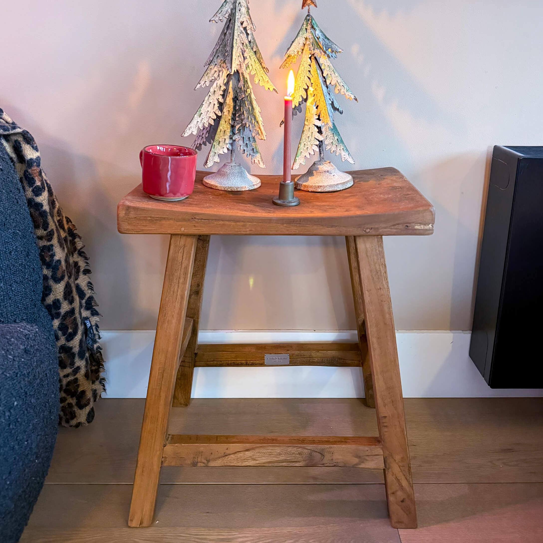Taburete de madera con árboles de metal decorativos y vela encendida en estilo industrial