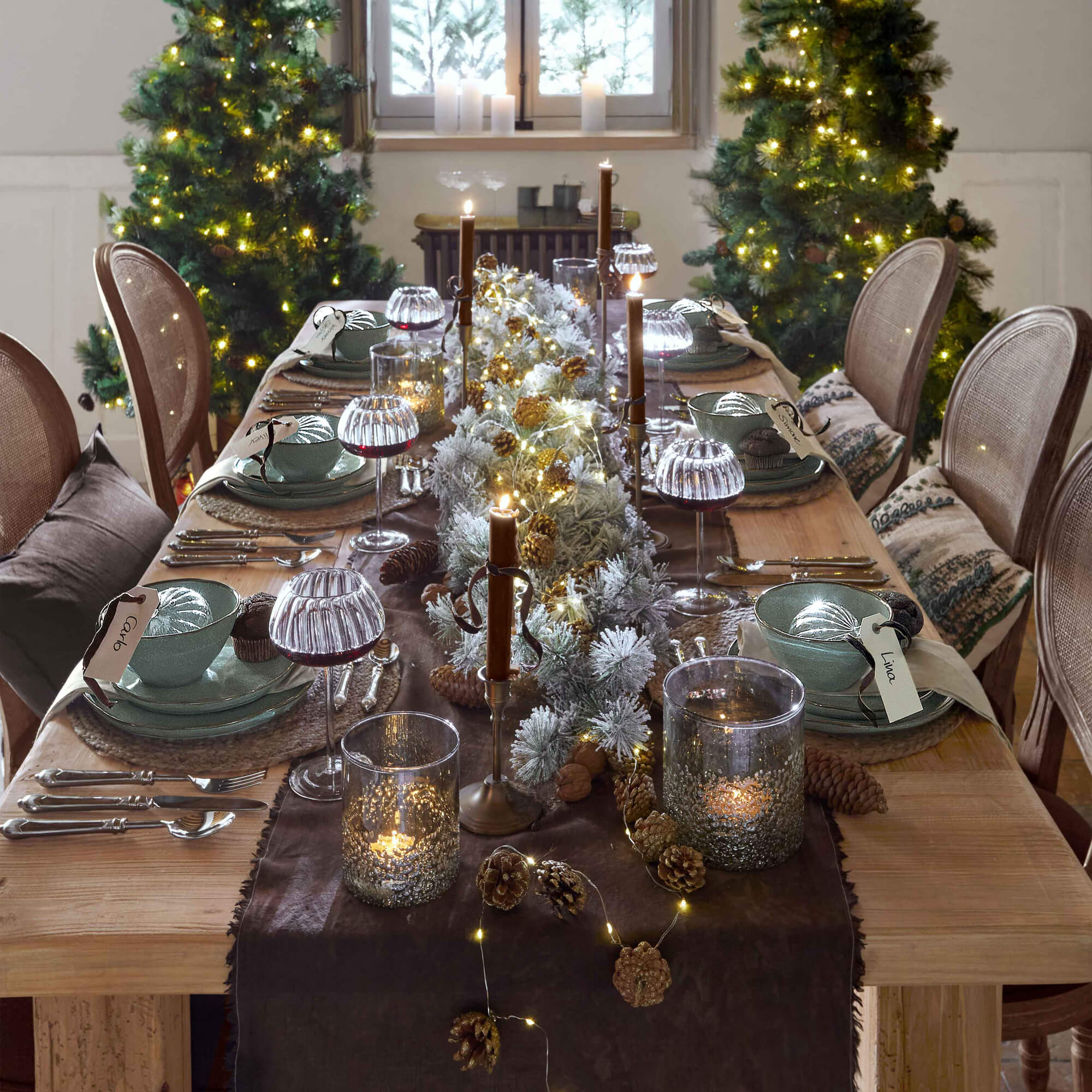Mesa de madera decorada para Navidad con vajilla verde, velas y luces LED