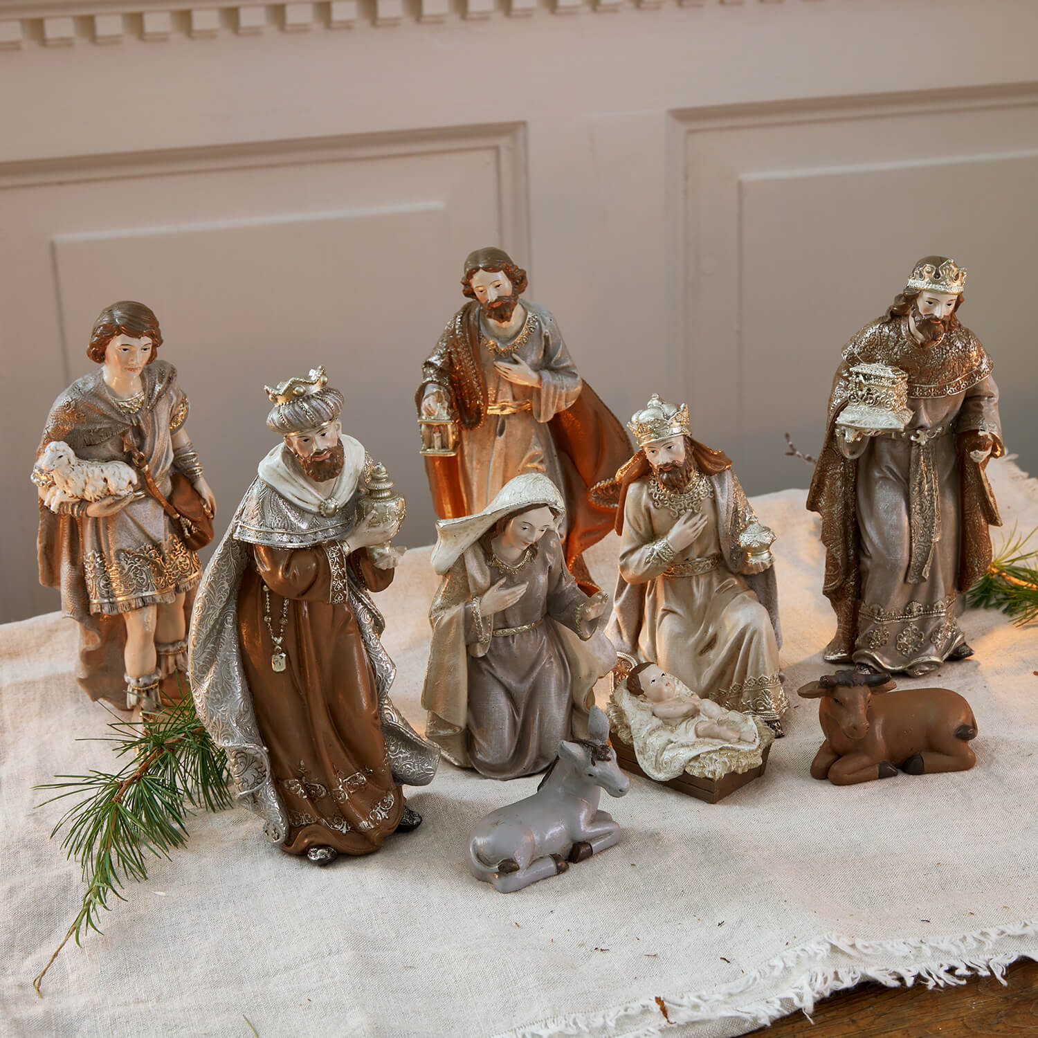 Conjunto de figuras de belén de resina en tonos marrones y grises sobre mantel de lino para decoración navideña