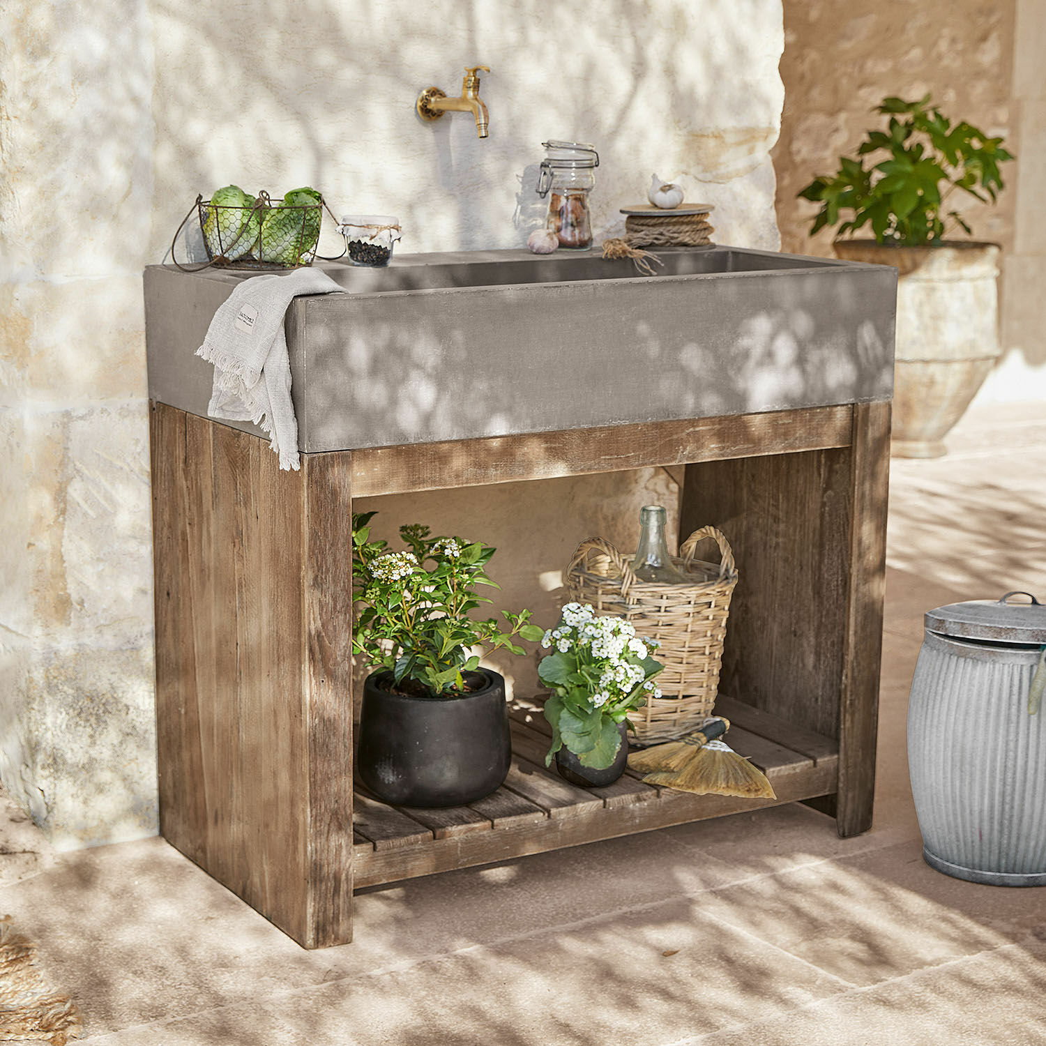 Mueble de lavabo Baines Lavabo de hormigón gris sobre base de madera con plantas y decoraciones en jardín soleado