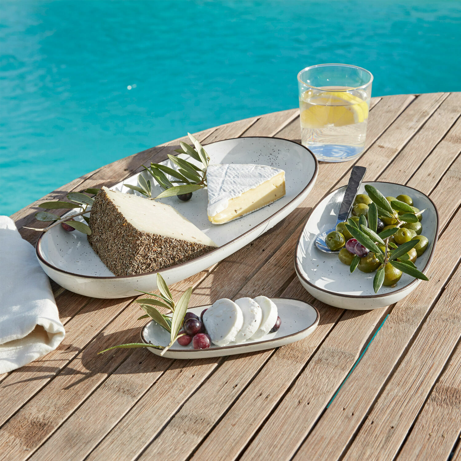 Set de 3 platos Biarré Juego de platos ovalados de cerámica crema sobre mesa de madera con quesos y aceitunas