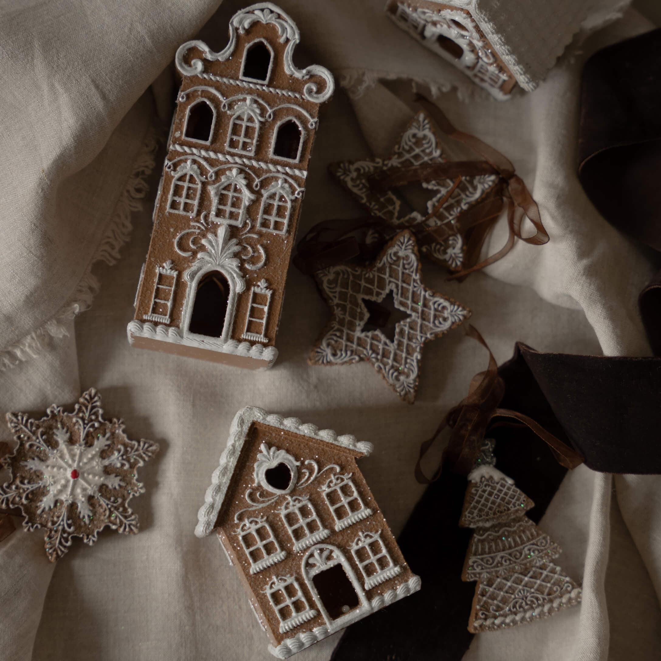 Casas y estrellas de jengibre decoradas con glaseado blanco sobre tela de lino, adornos navideños