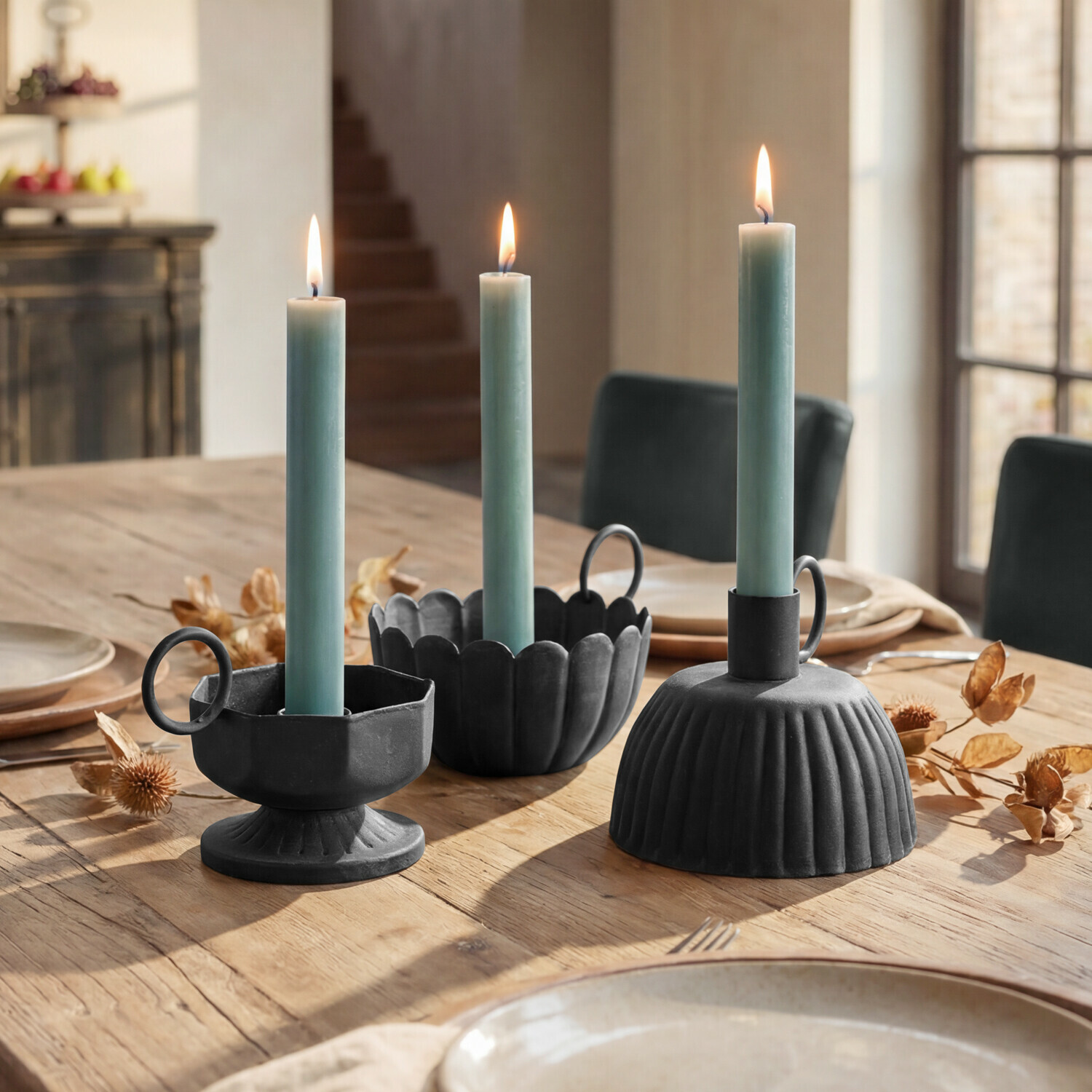 Set de 3 candeleros Lazharin Tres candelabros de metal negro con velas verdes sobre mesa de madera en comedor