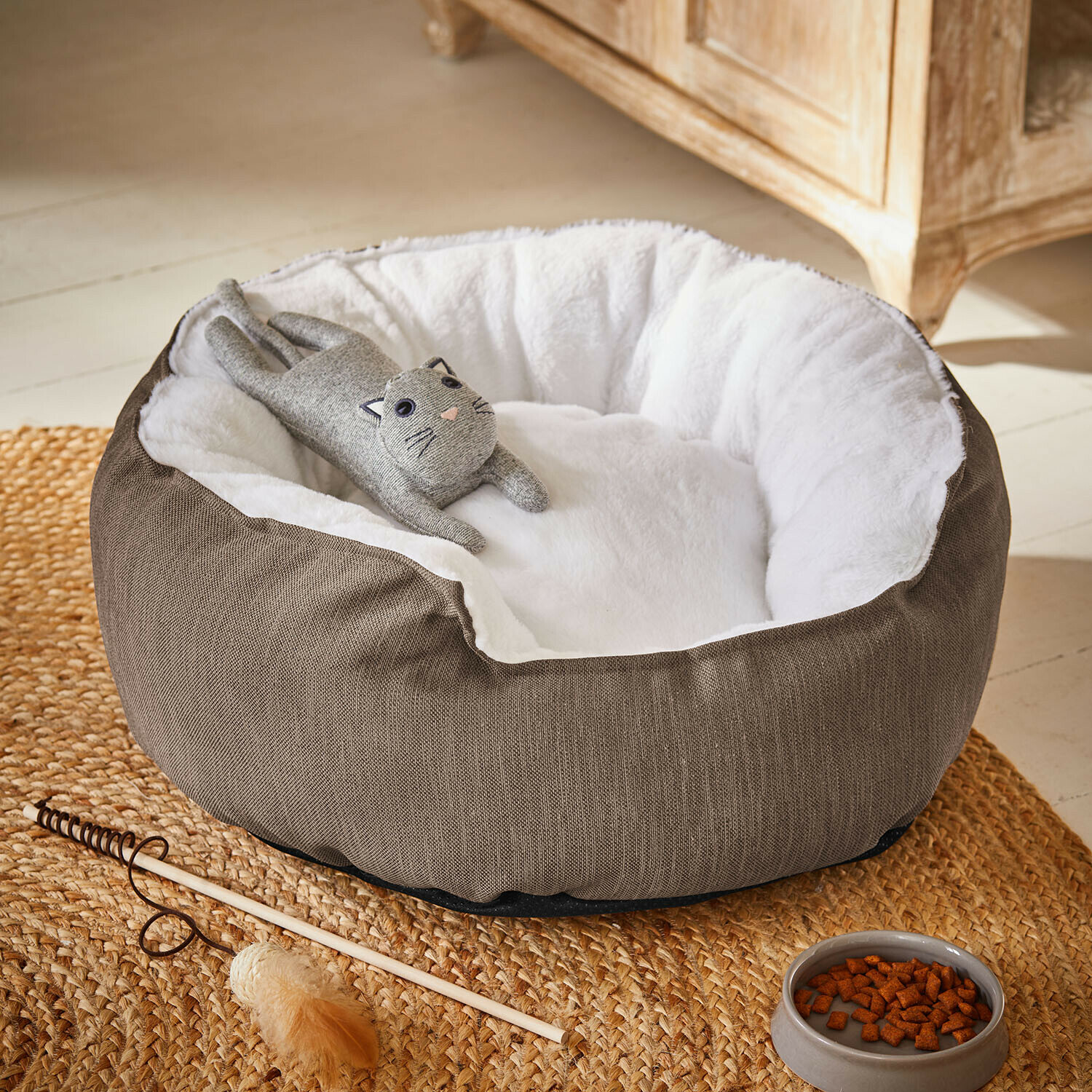 Cama para mascotas Camérelle Cama para gato marrón con interior blanco suave y juguete de gato gris tumbado encima