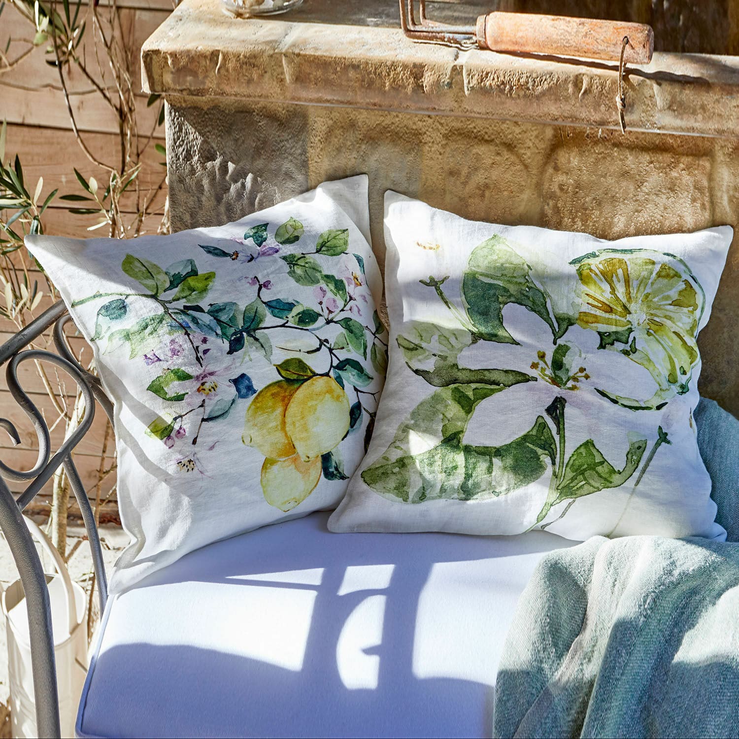 Cojines de lino blanco con estampado de limones y hojas verdes, decoración de jardín en banco metálico