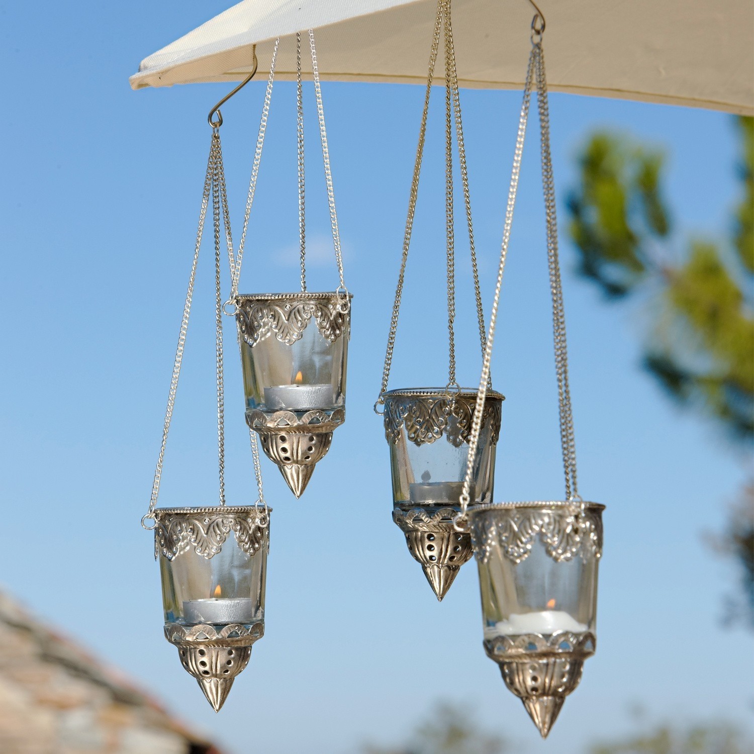 Set de 4 farolillos Céleste Conjunto de cuatro portavelas colgantes de vidrio y metal plateado con cadenas para decoración exterior