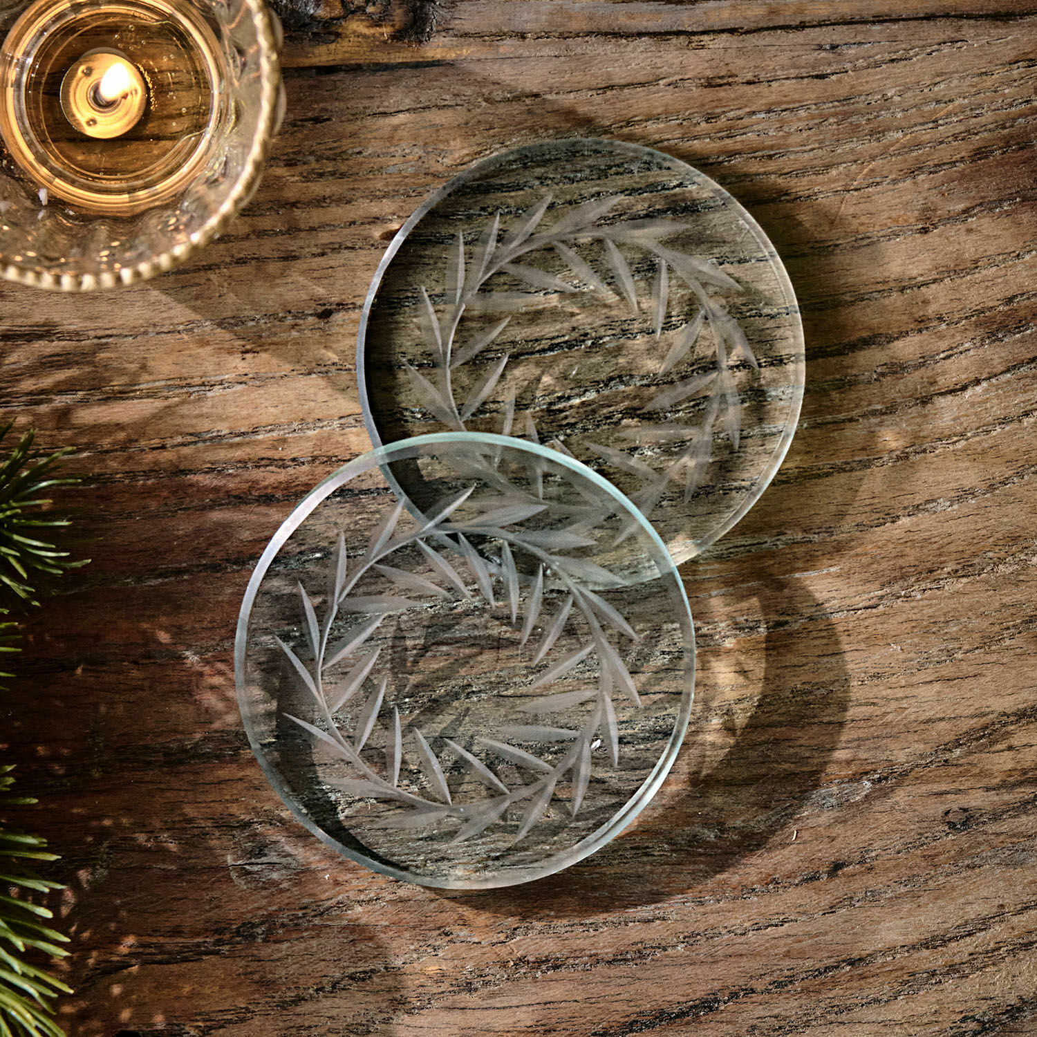 Set de 2 posavasos Altheris Posavasos de vidrio transparente con diseño grabado de hojas sobre mesa de madera, decoración elegante