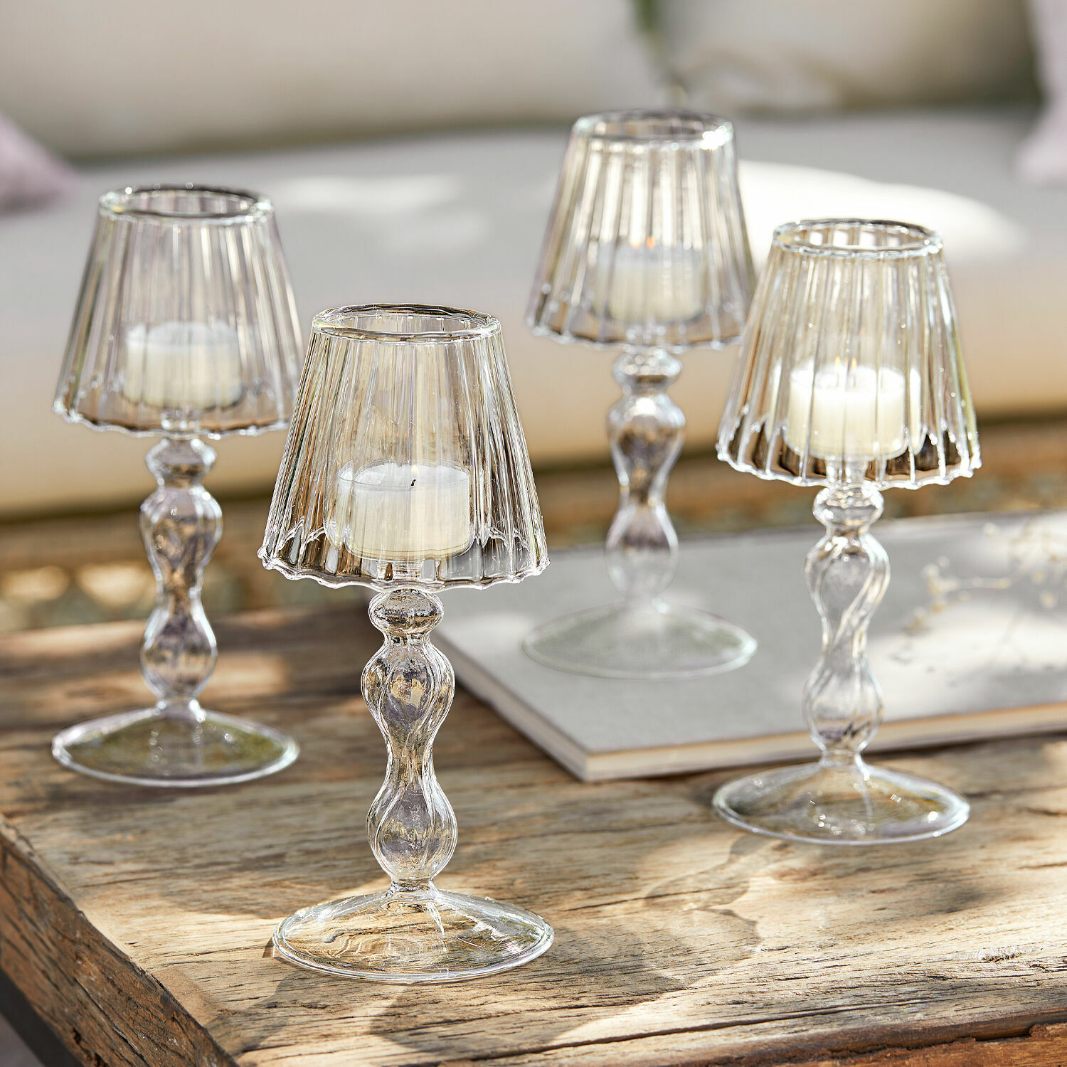 Set de 4 candeleros Jouval Portavelas de vidrio con velas blancas sobre mesa de madera, decoración interior elegante