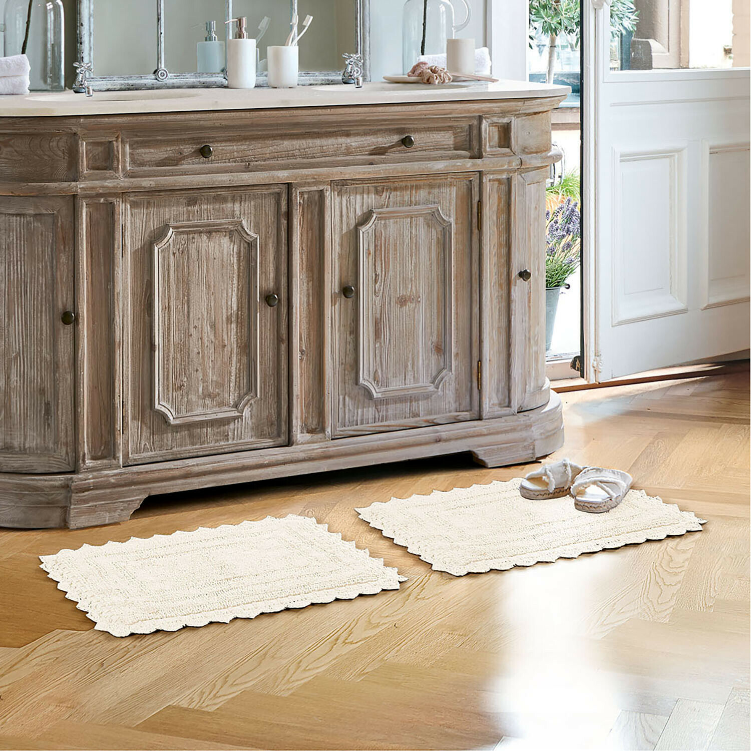 Alfombrilla de baño Yalexir Mueble de madera estilo vintage con dos alfombras crema sobre suelo claro en baño luminoso