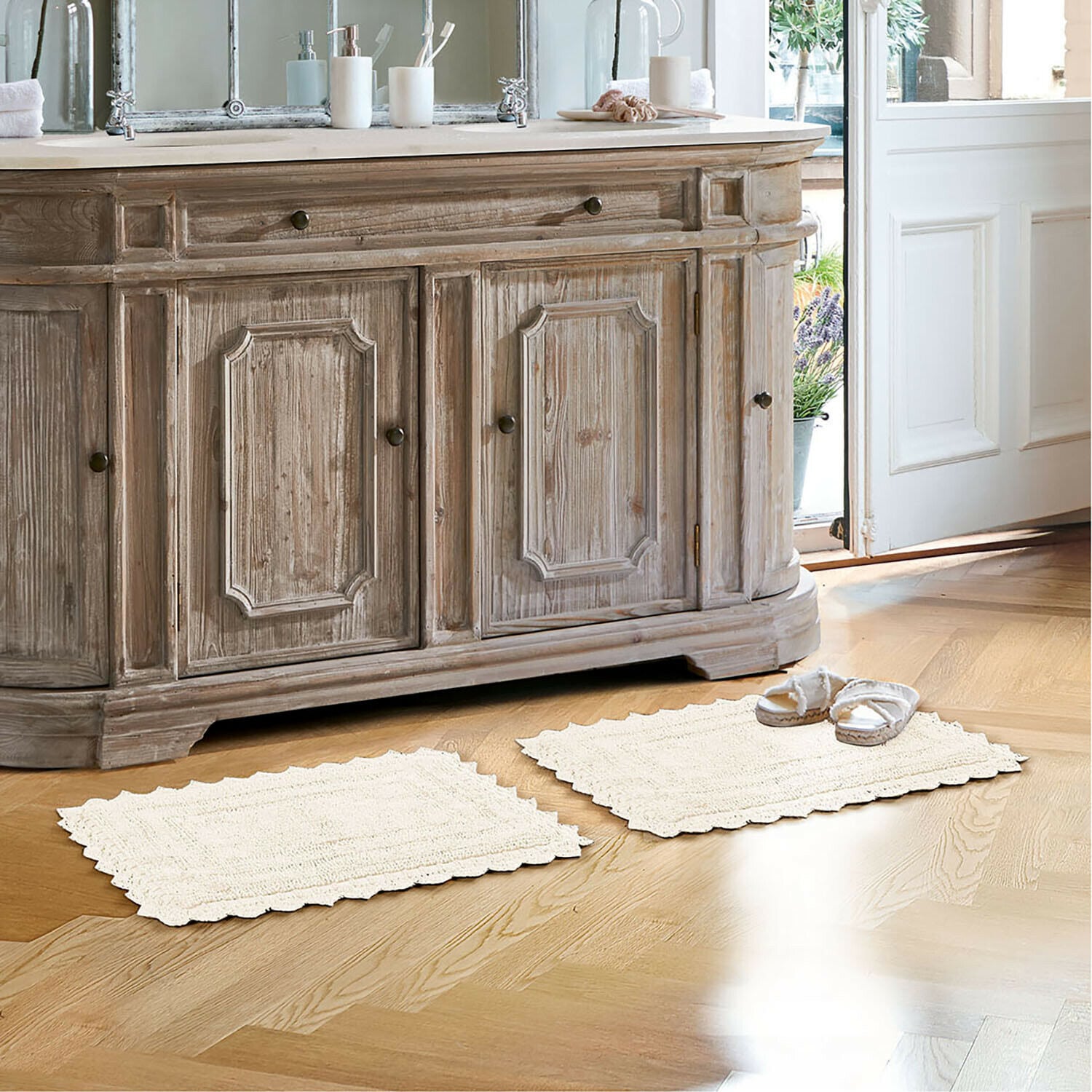 Alfombrilla de baño Yalexir Mueble de madera estilo vintage con dos alfombras crema sobre suelo claro en baño luminoso