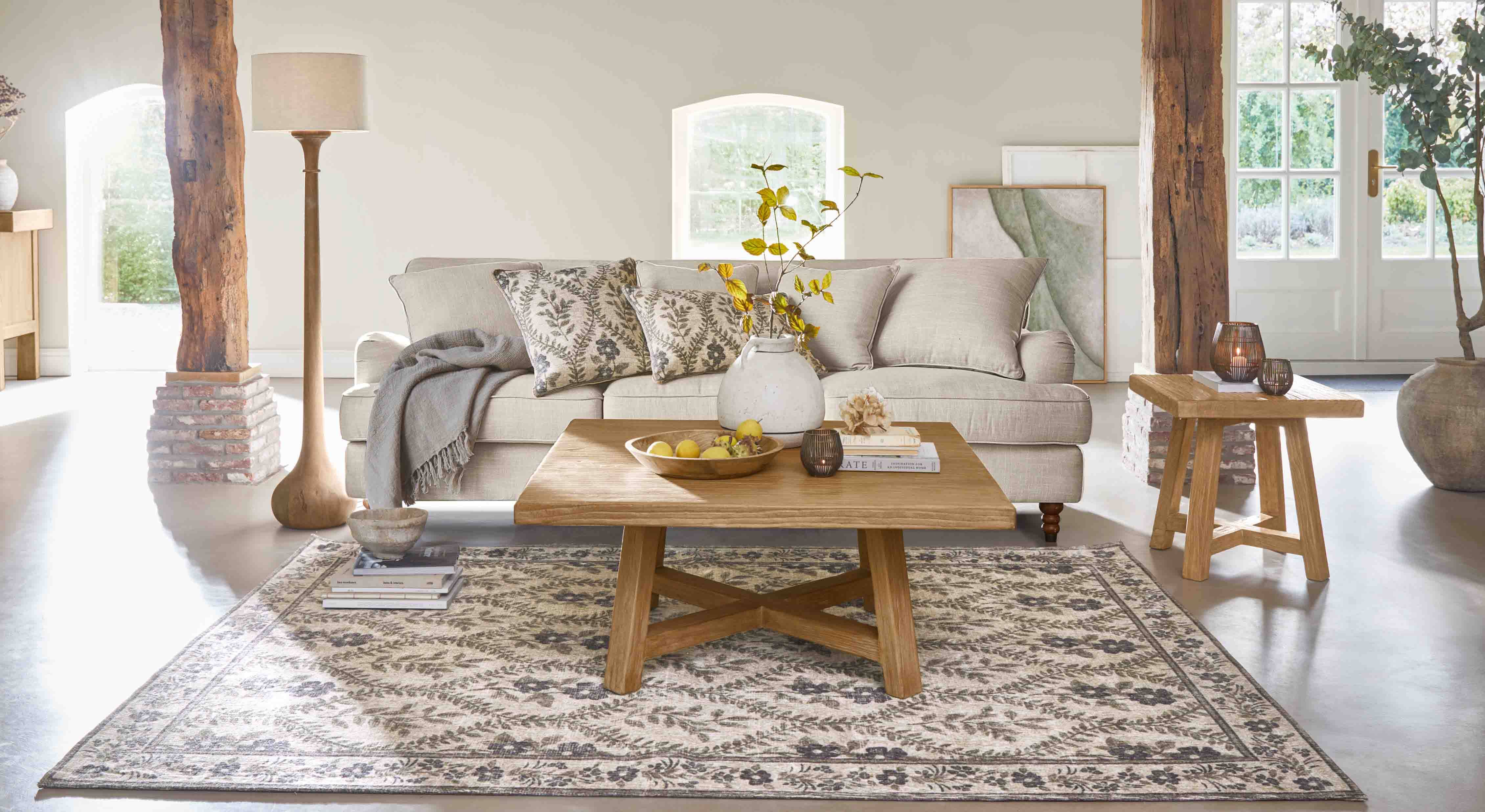 Salón acogedor con sofá beige, mesa de madera y alfombra decorativa con diseño floral